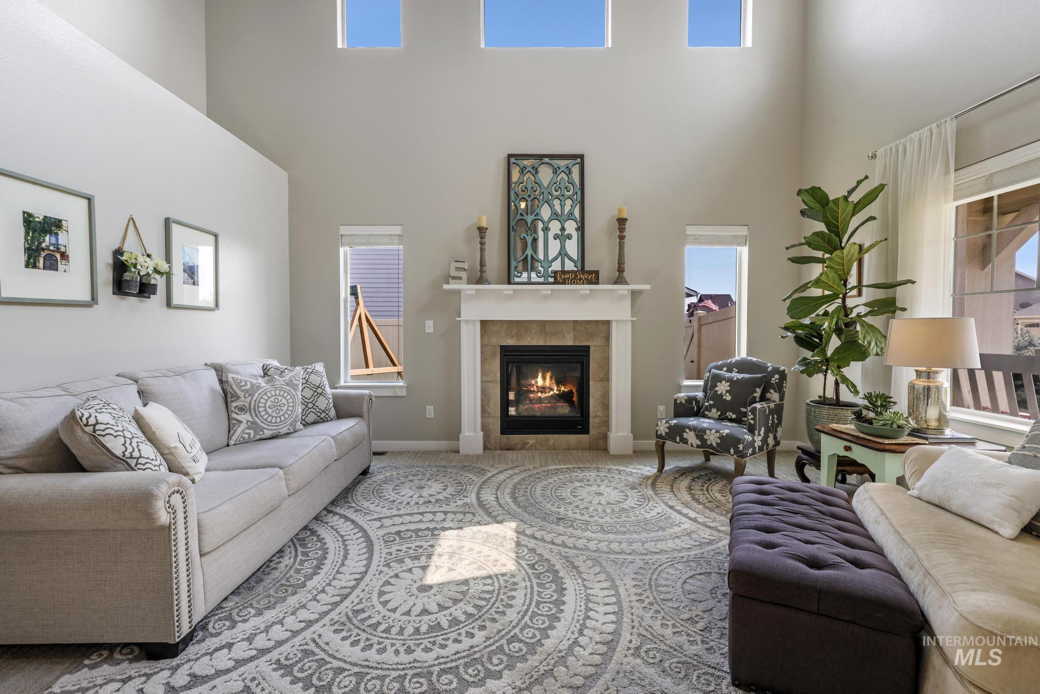 Carpeted living area with a tiled fireplace and a towering ceiling