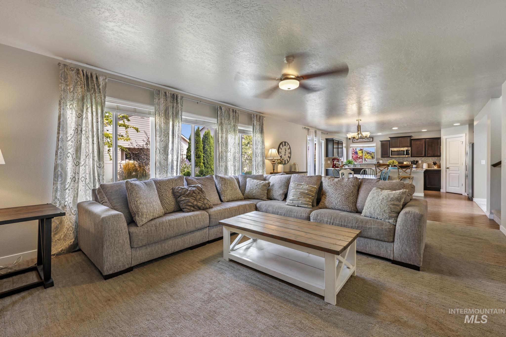 Living area featuring a textured ceiling, a chandelier, and a ceiling fan