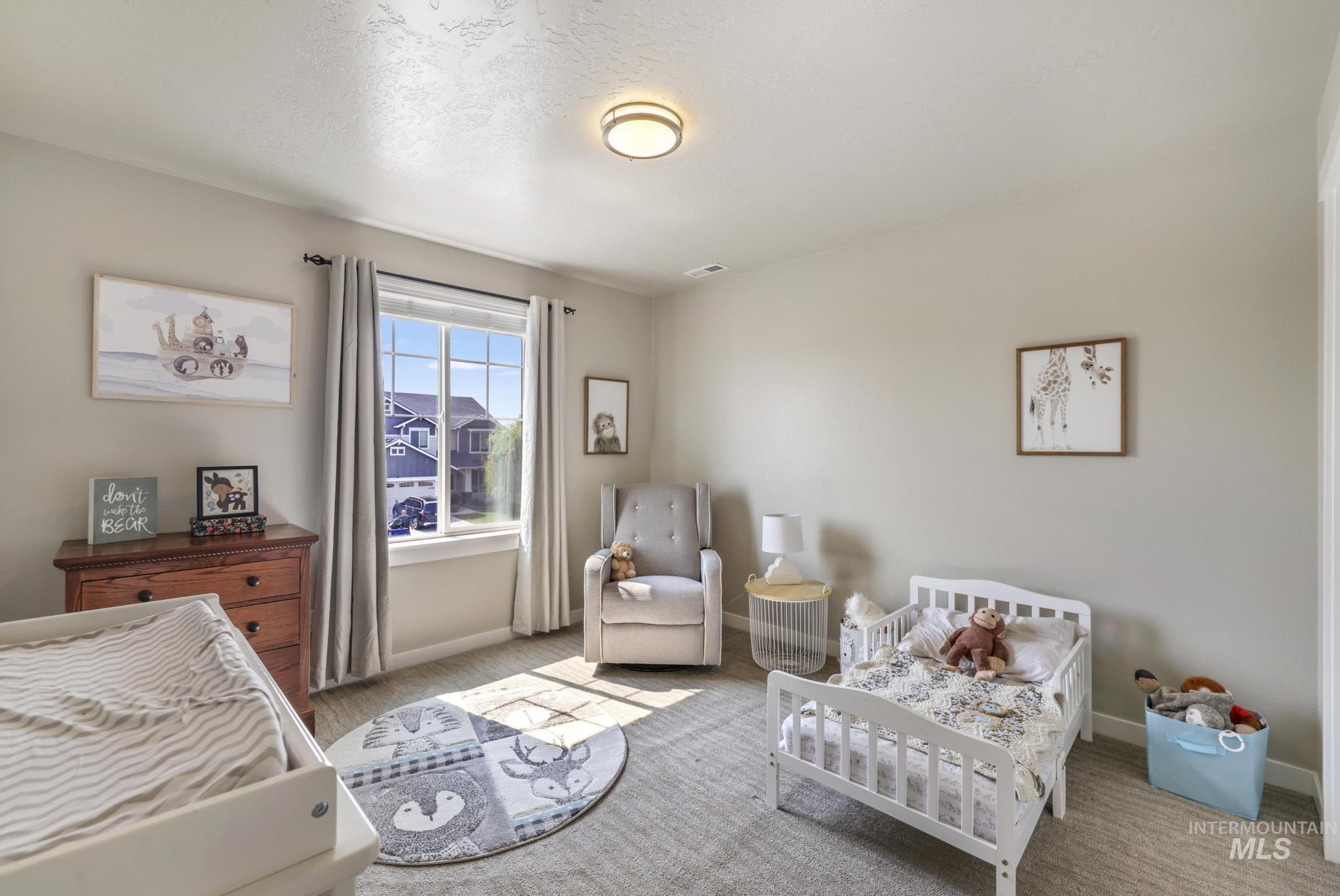 Bedroom featuring a crib, carpet, and a textured ceiling