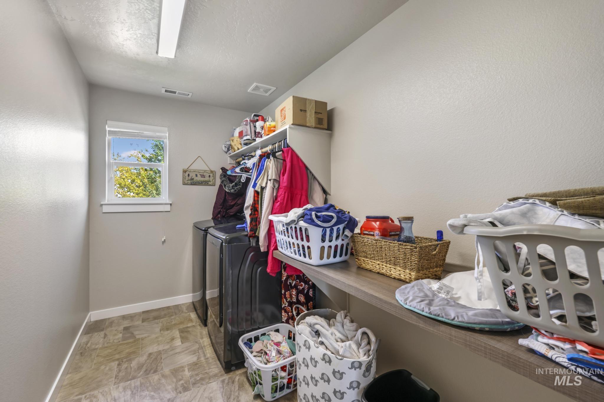 Laundry room featuring stone finish floors, a textured wall, and separate washer and dryer