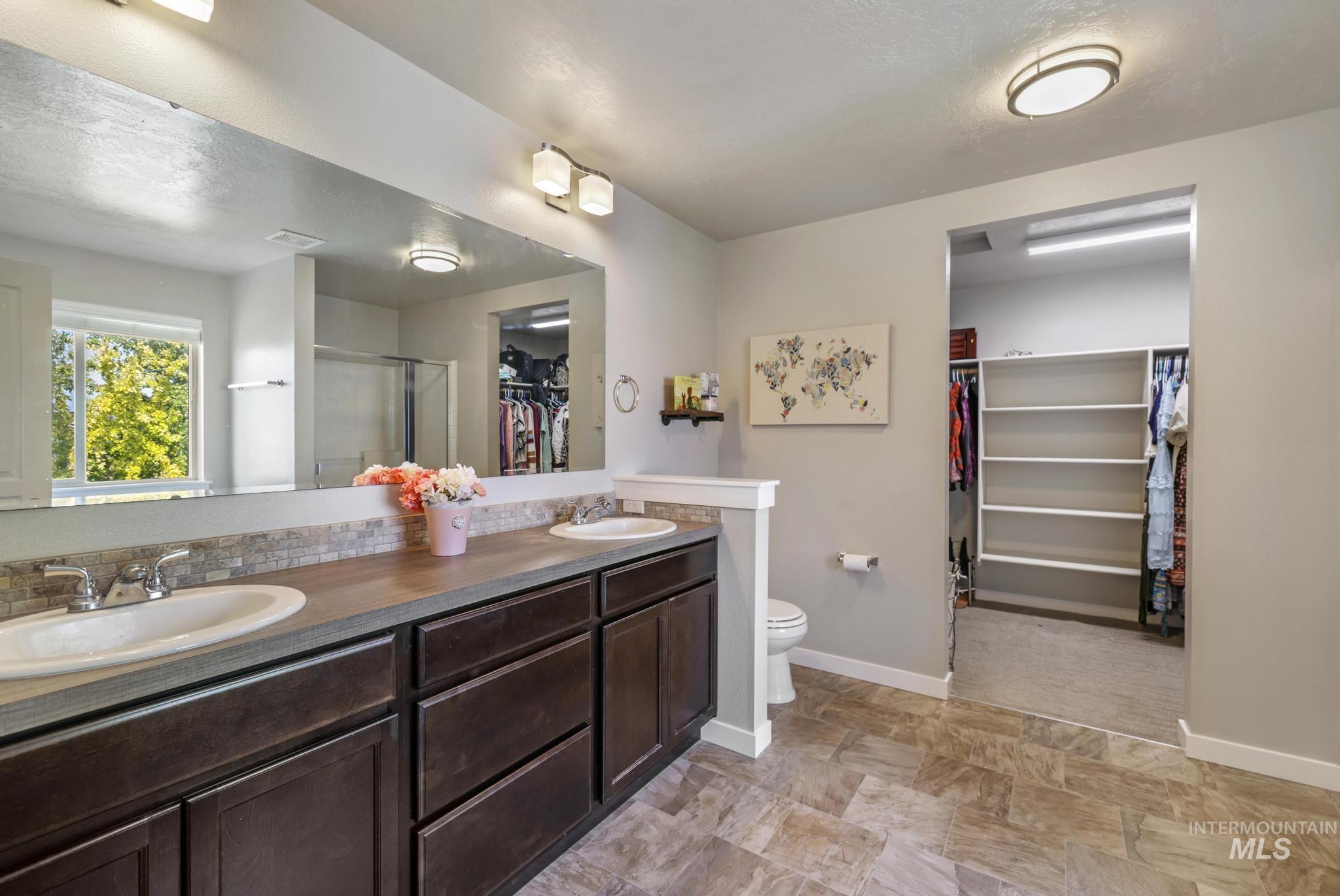 Bathroom with a walk in closet, double vanity, a stall shower, and a textured ceiling