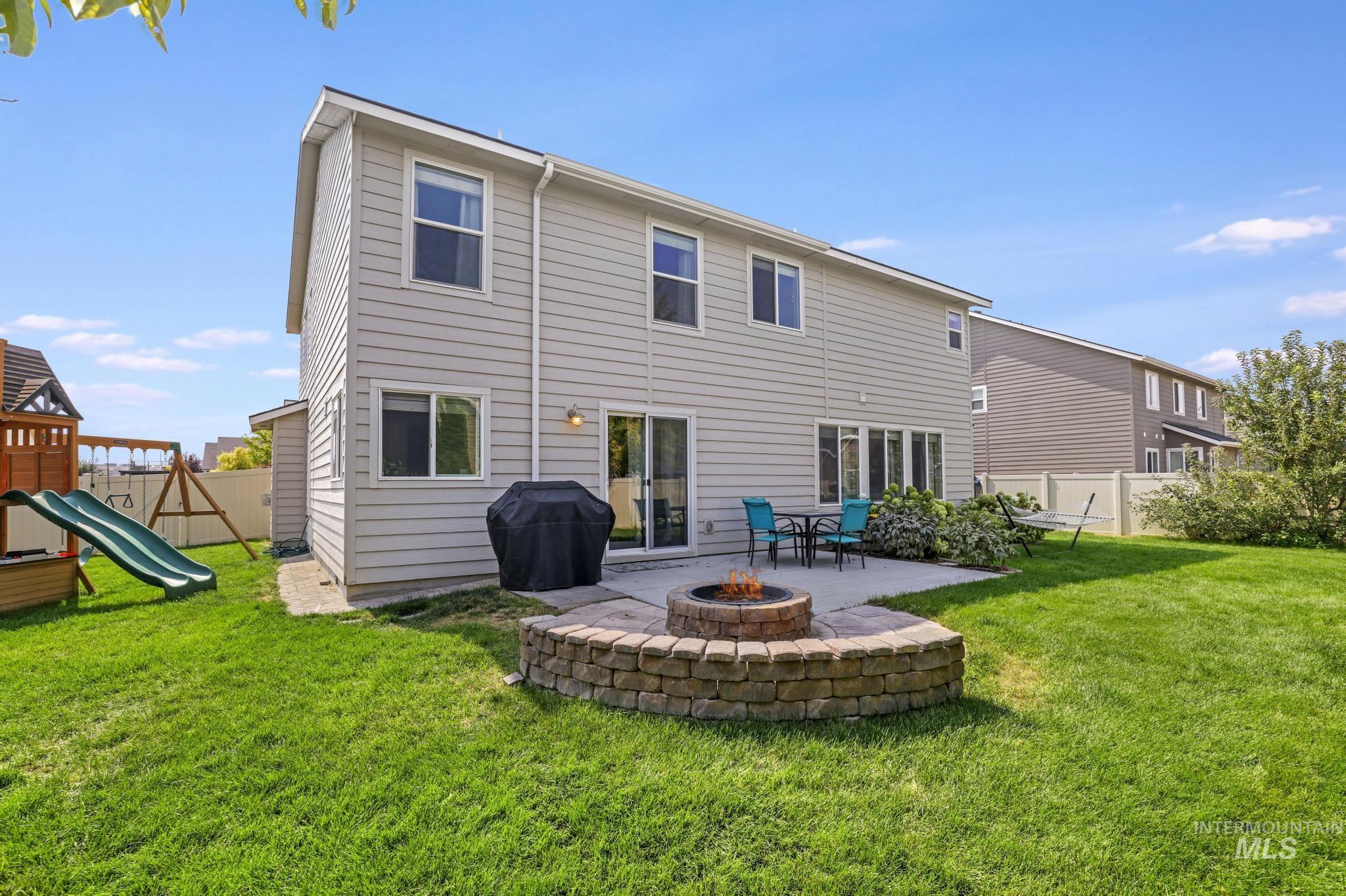 Rear view of property featuring a playground, a patio, and a fire pit