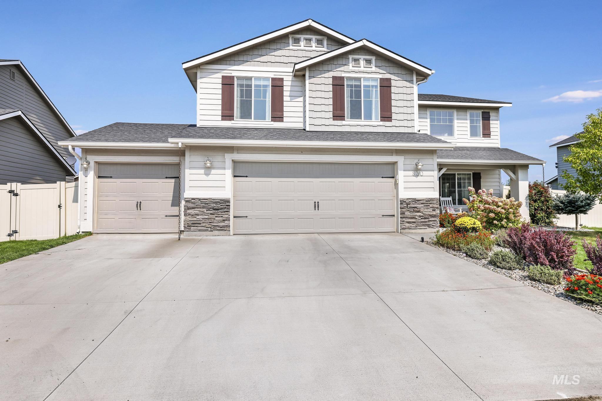 Craftsman-style home with stone siding, an attached garage, driveway, and a shingled roof