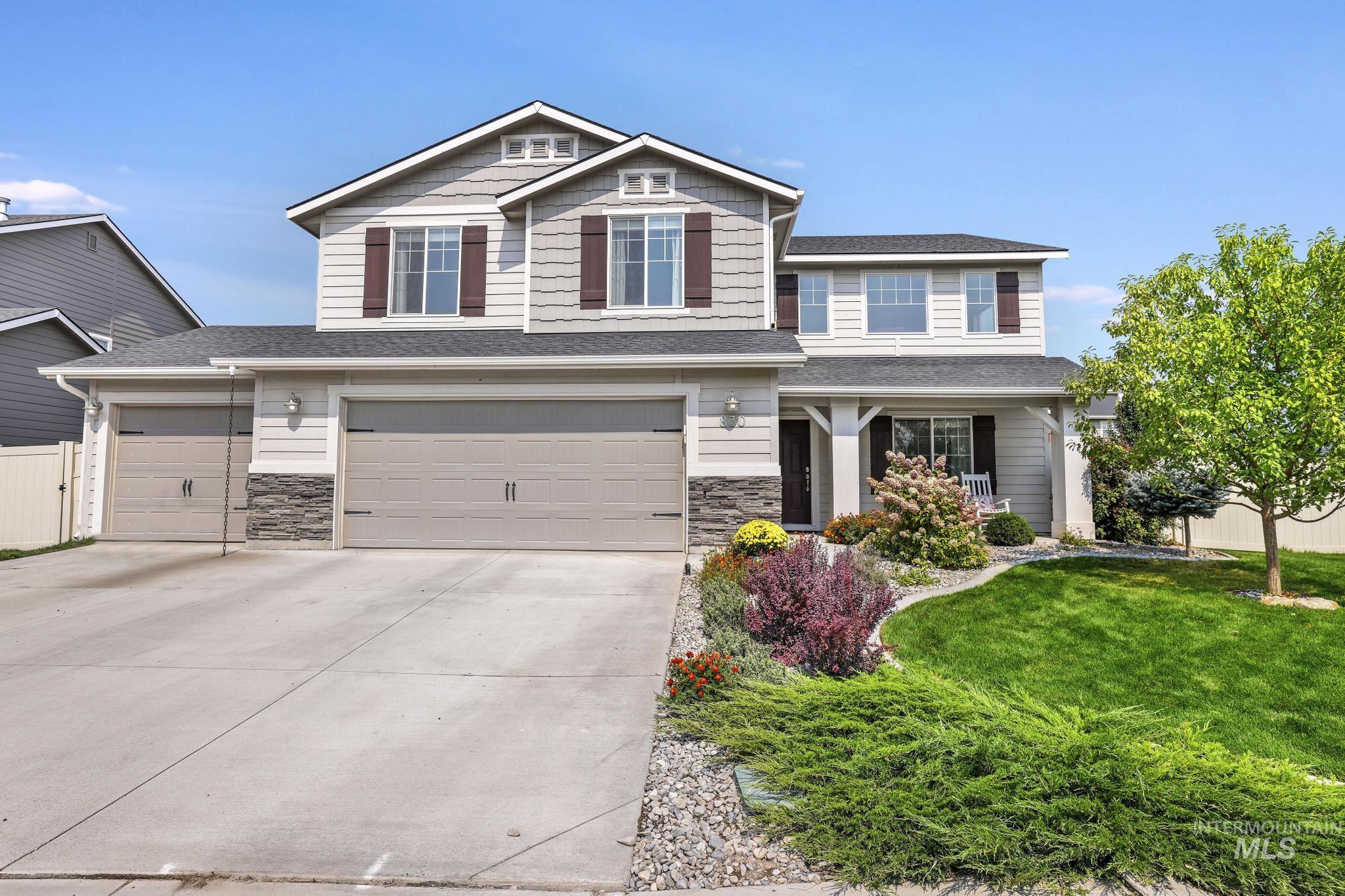 Craftsman-style house with a shingled roof, driveway, stone siding, a garage, and covered porch