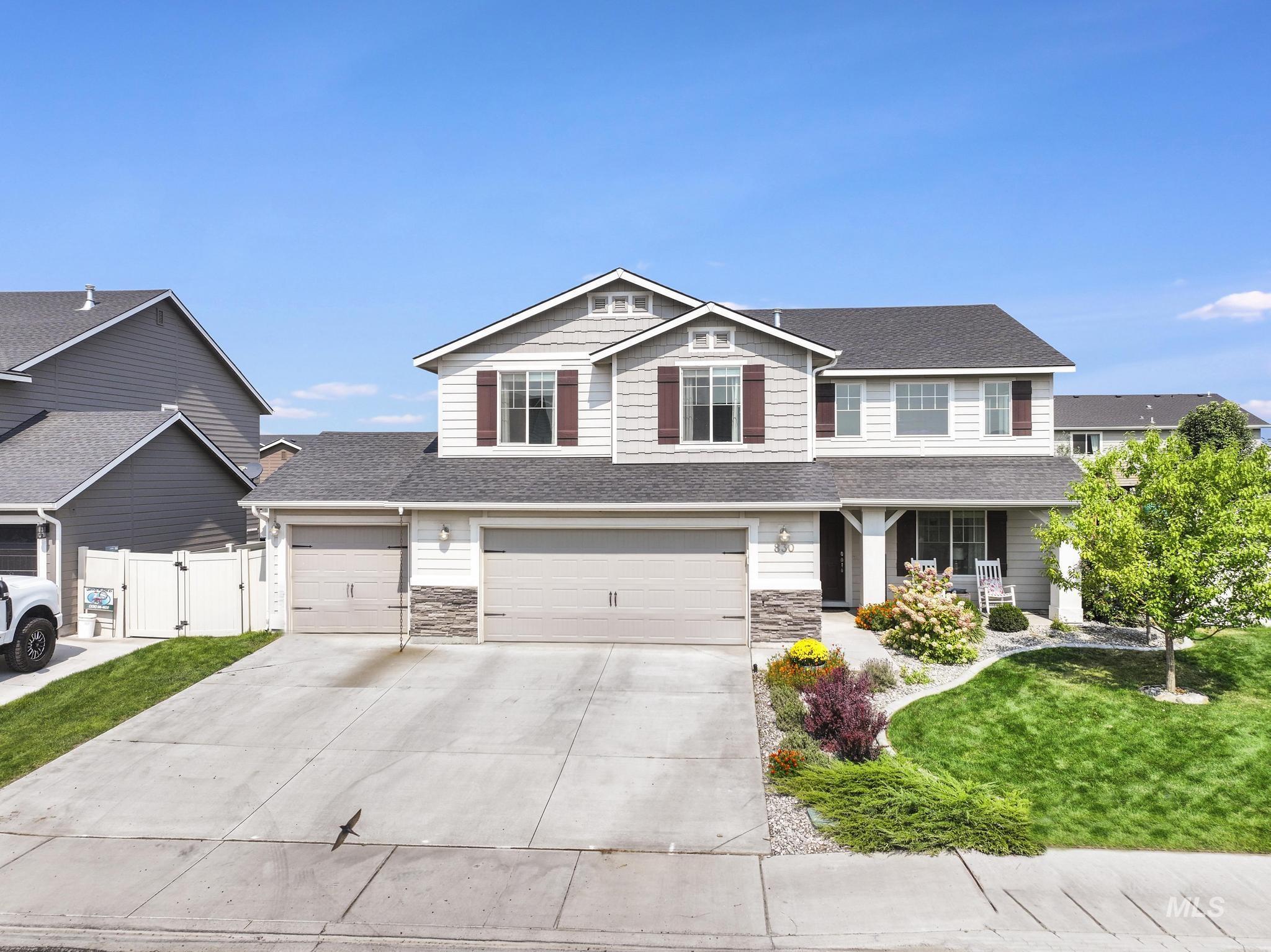 Craftsman-style house featuring a shingled roof, driveway, stone siding, and a porch