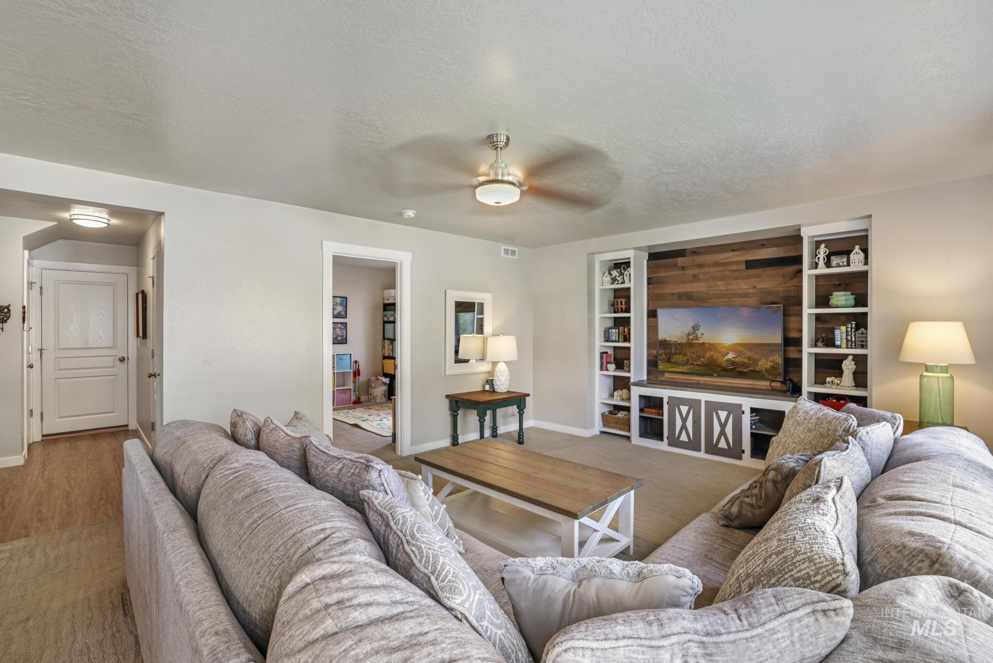 Carpeted living area featuring a textured ceiling and ceiling fan