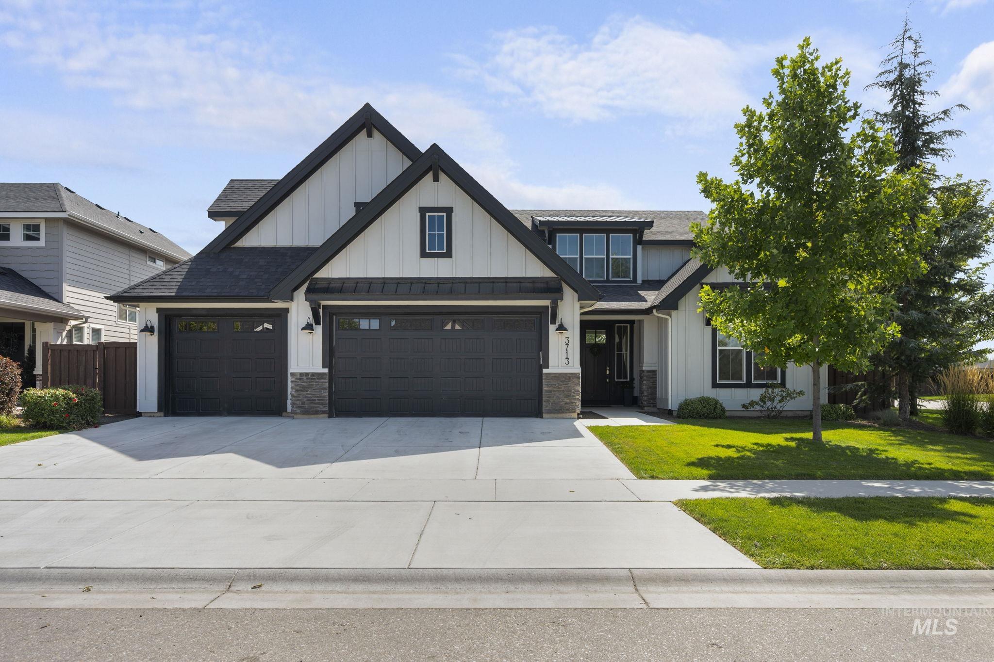 Modern farmhouse featuring board and batten siding, driveway, and roof with shingles
