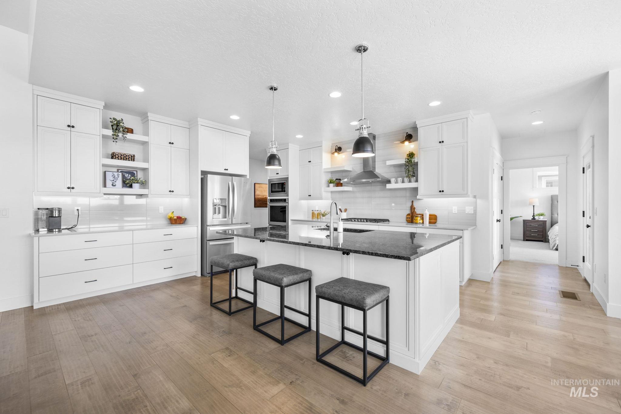 Kitchen with open shelves, white cabinetry, dark stone countertops, appliances with stainless steel finishes, and hanging light fixtures