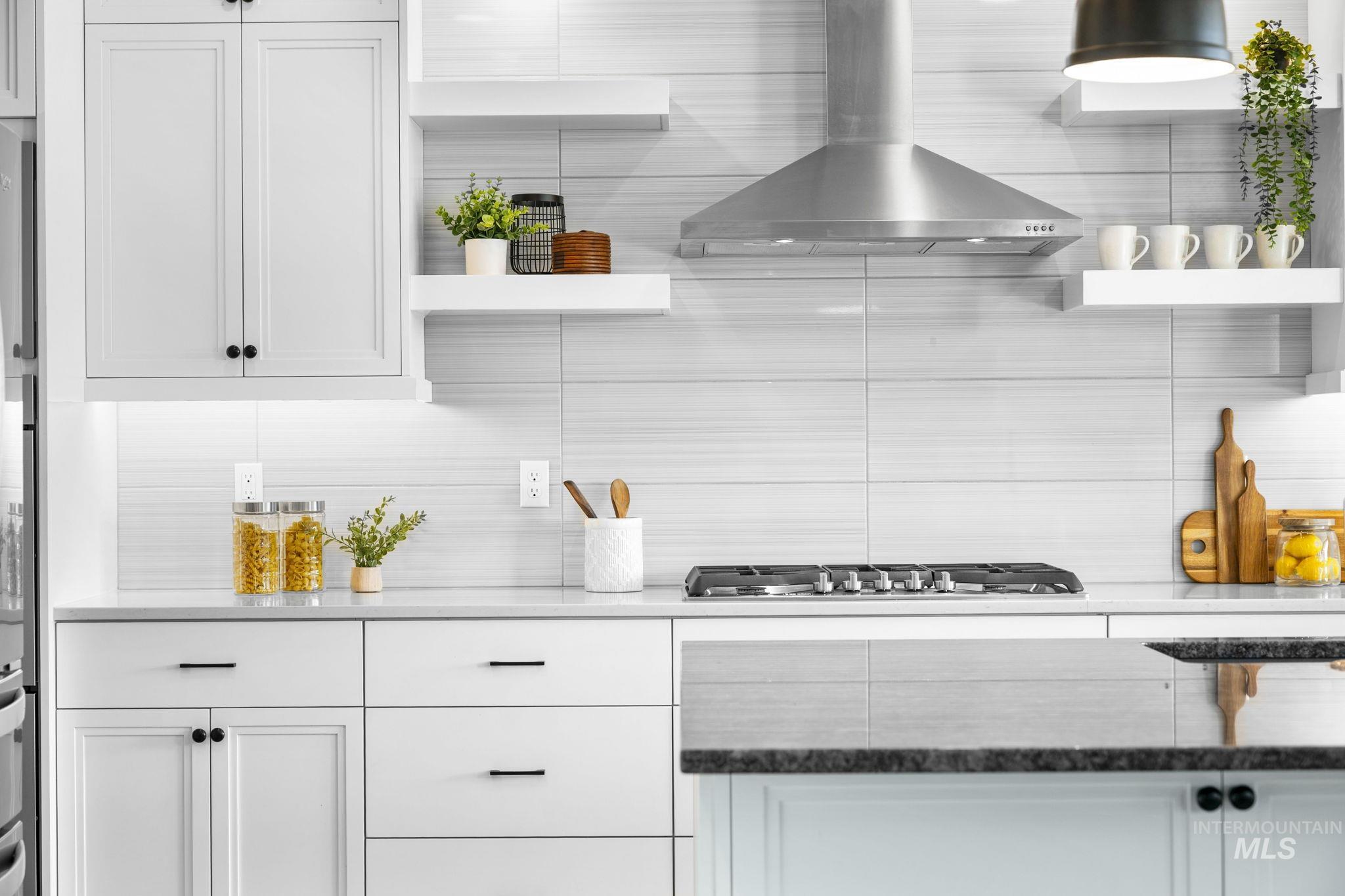 Kitchen featuring open shelves, wall chimney range hood, white cabinetry, dark stone counters, and stainless steel gas stovetop