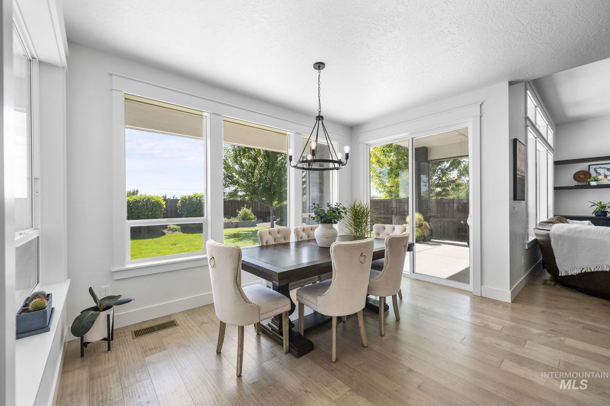 Dining area with light wood-style floors, a chandelier, and a textured ceiling
