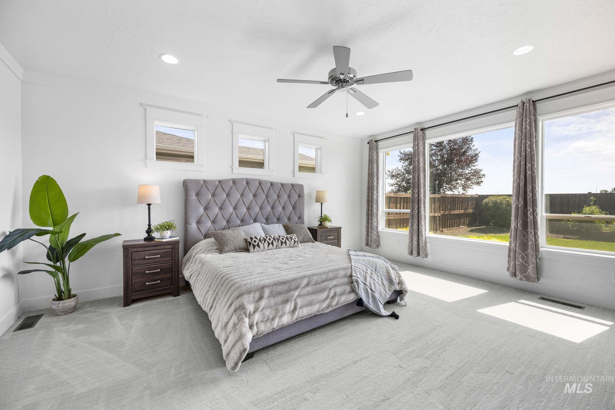 Carpeted, main level primary bedroom with a ceiling fan, recessed lighting, and private door to backyard patio.
