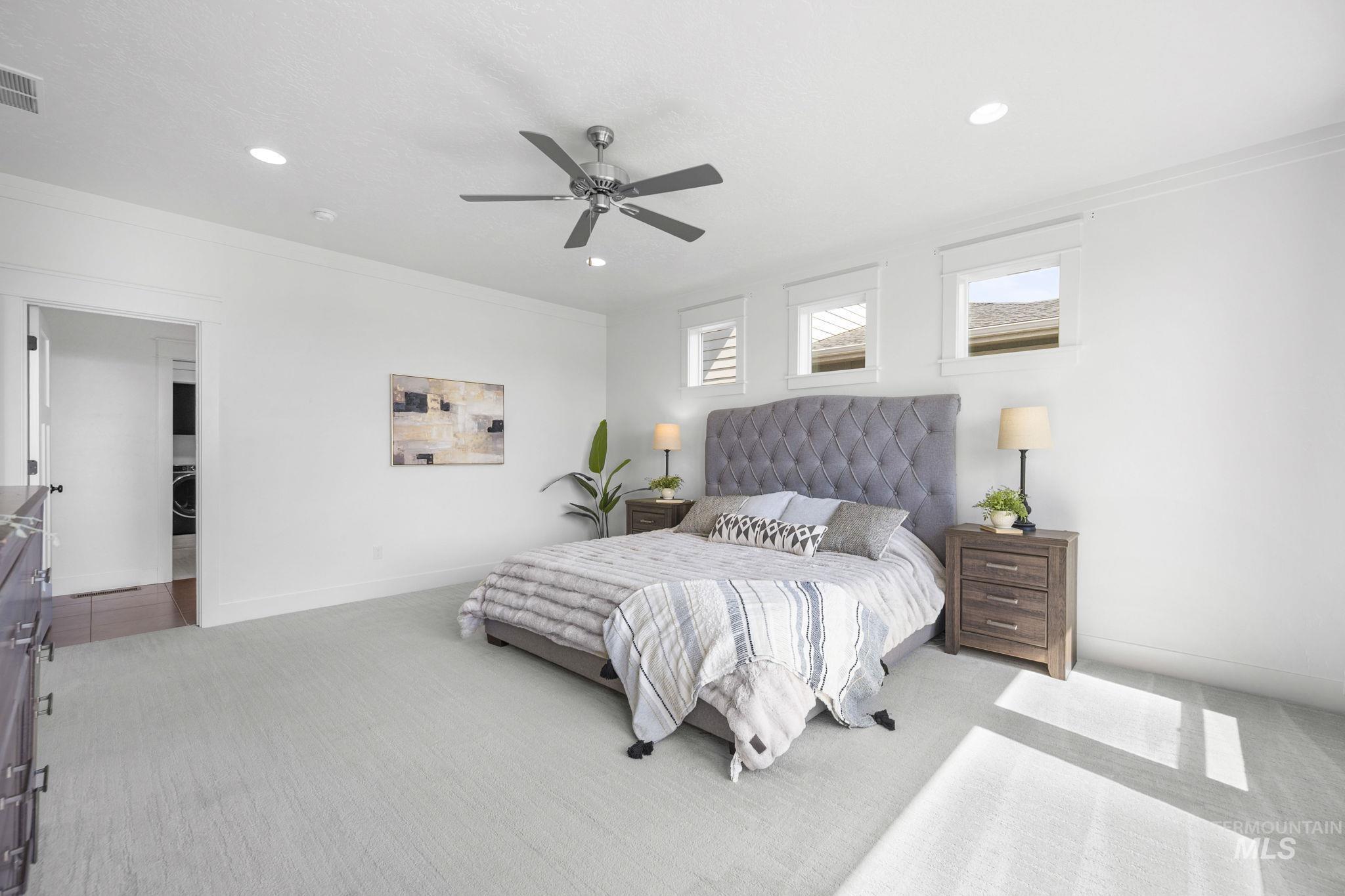 Primary bedroom with recessed lighting, light carpet, and ceiling fan.
