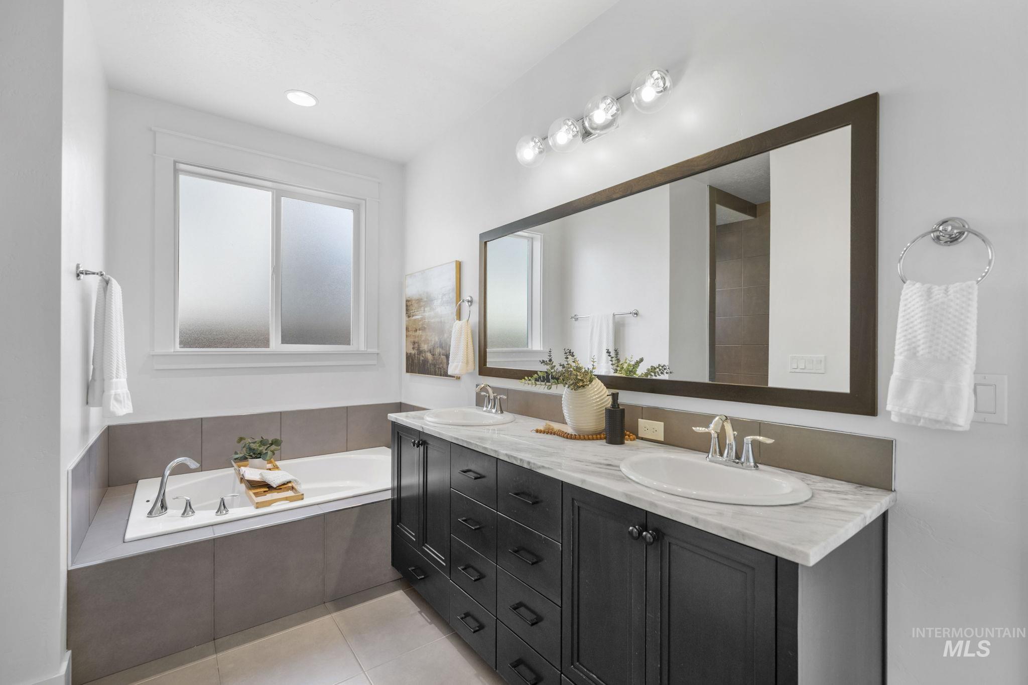 Full primary bathroom featuring double vanity, a bath, light tile patterned flooring, and recessed lighting