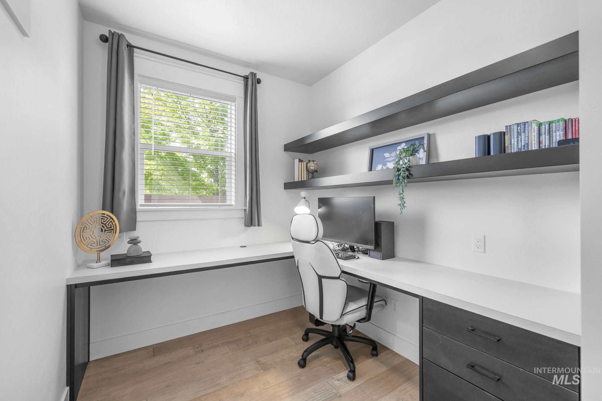 Main level office featuring built in study area and light wood-style floors