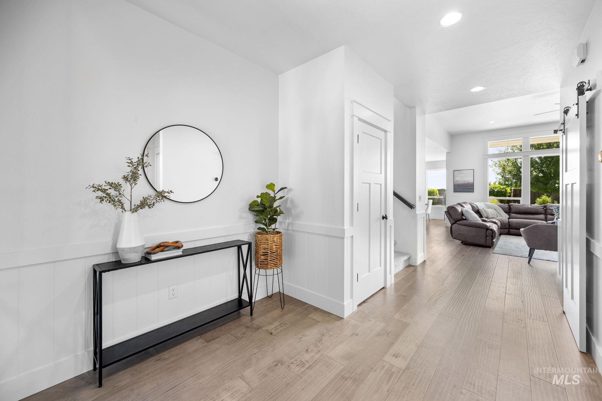 Entry hallway with light wood-style floors, a barn door, recessed lighting, a wainscoted wall, and stairway