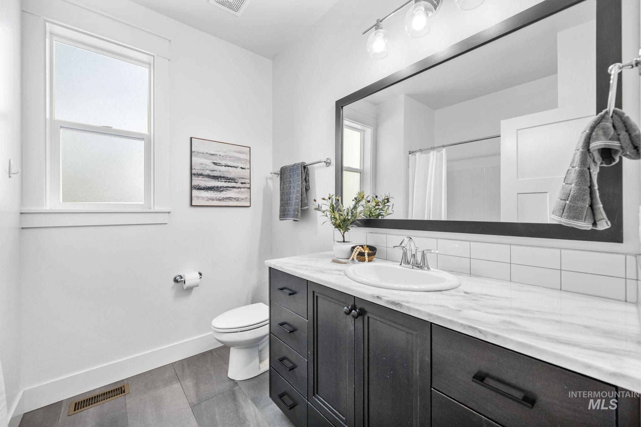 Main level, full bathroom featuring vanity, tasteful backsplash, and a shower with shower curtain