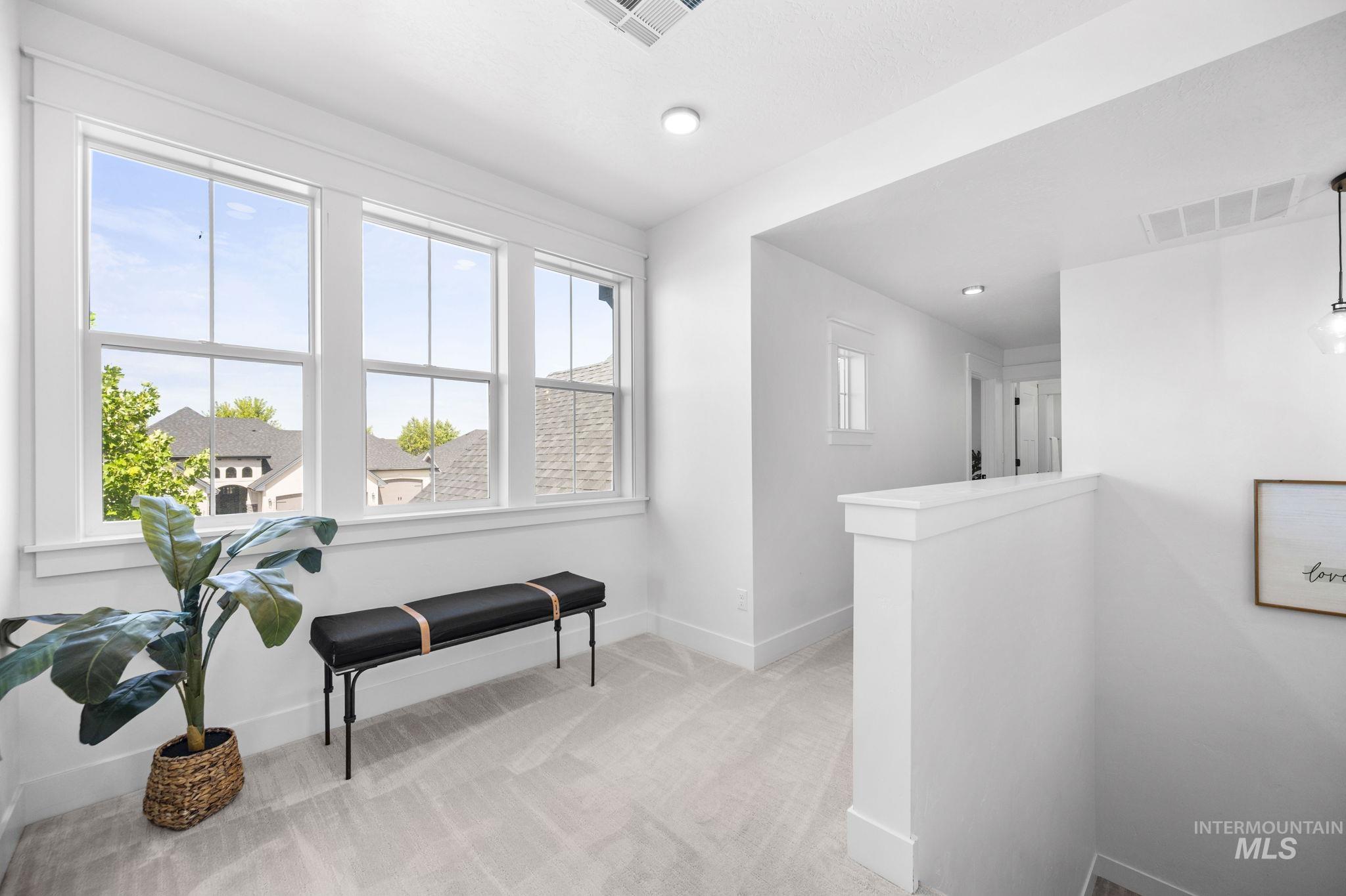 Top of stair case landing hallway, second story, featuring light carpet and baseboards