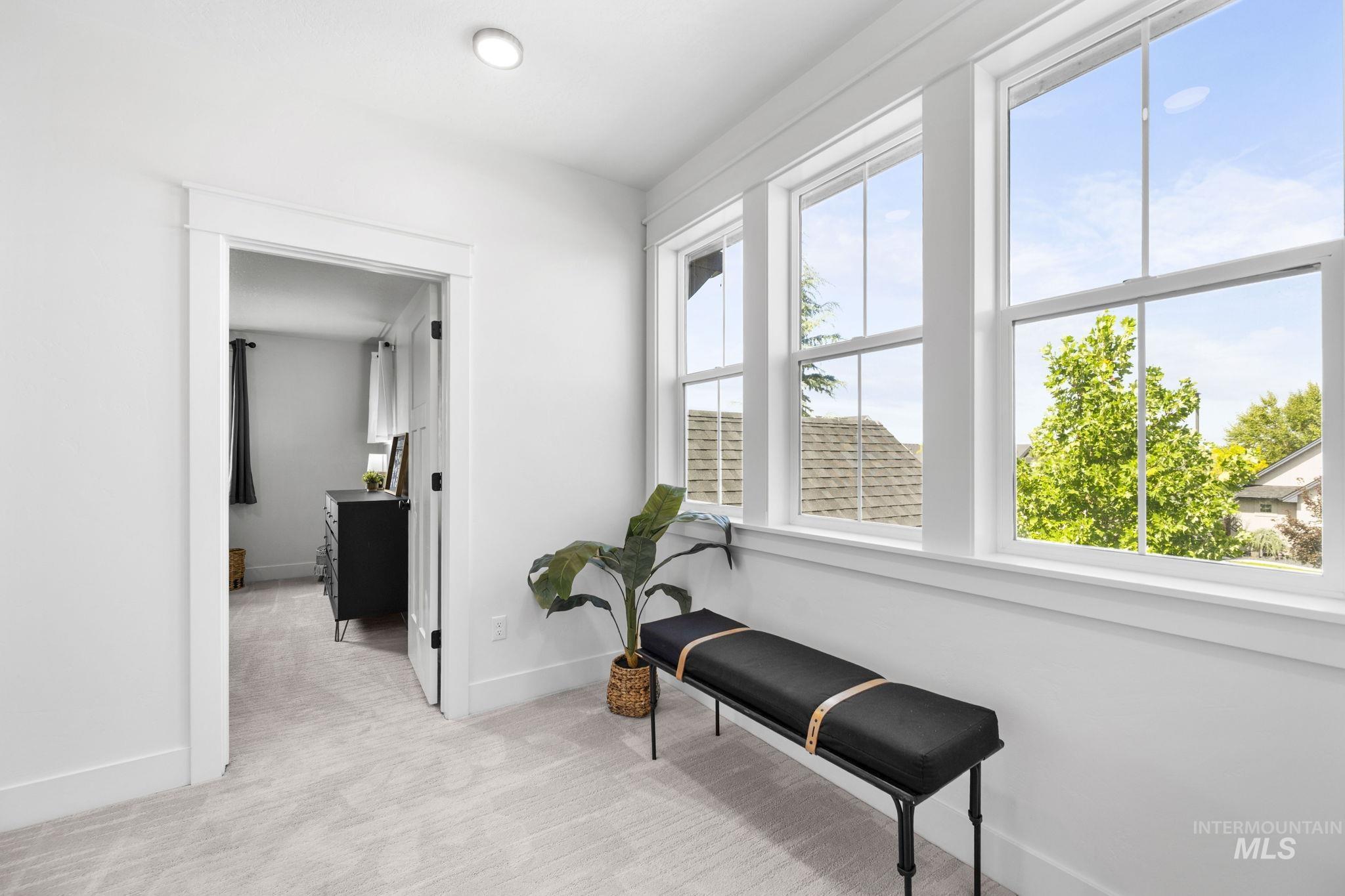 Top of staircase landing hallway, second story, featuring light carpet and baseboards
