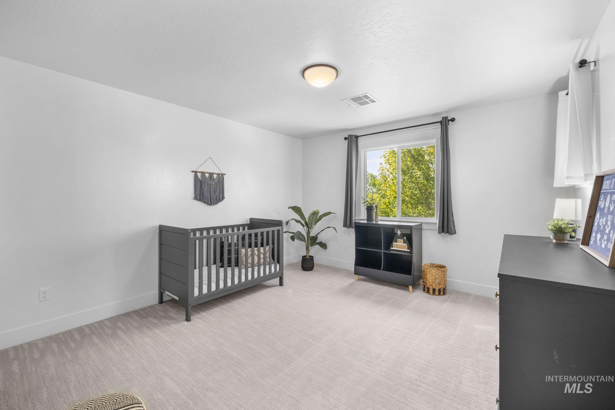 Second story bedroom with a nursery area and light carpet