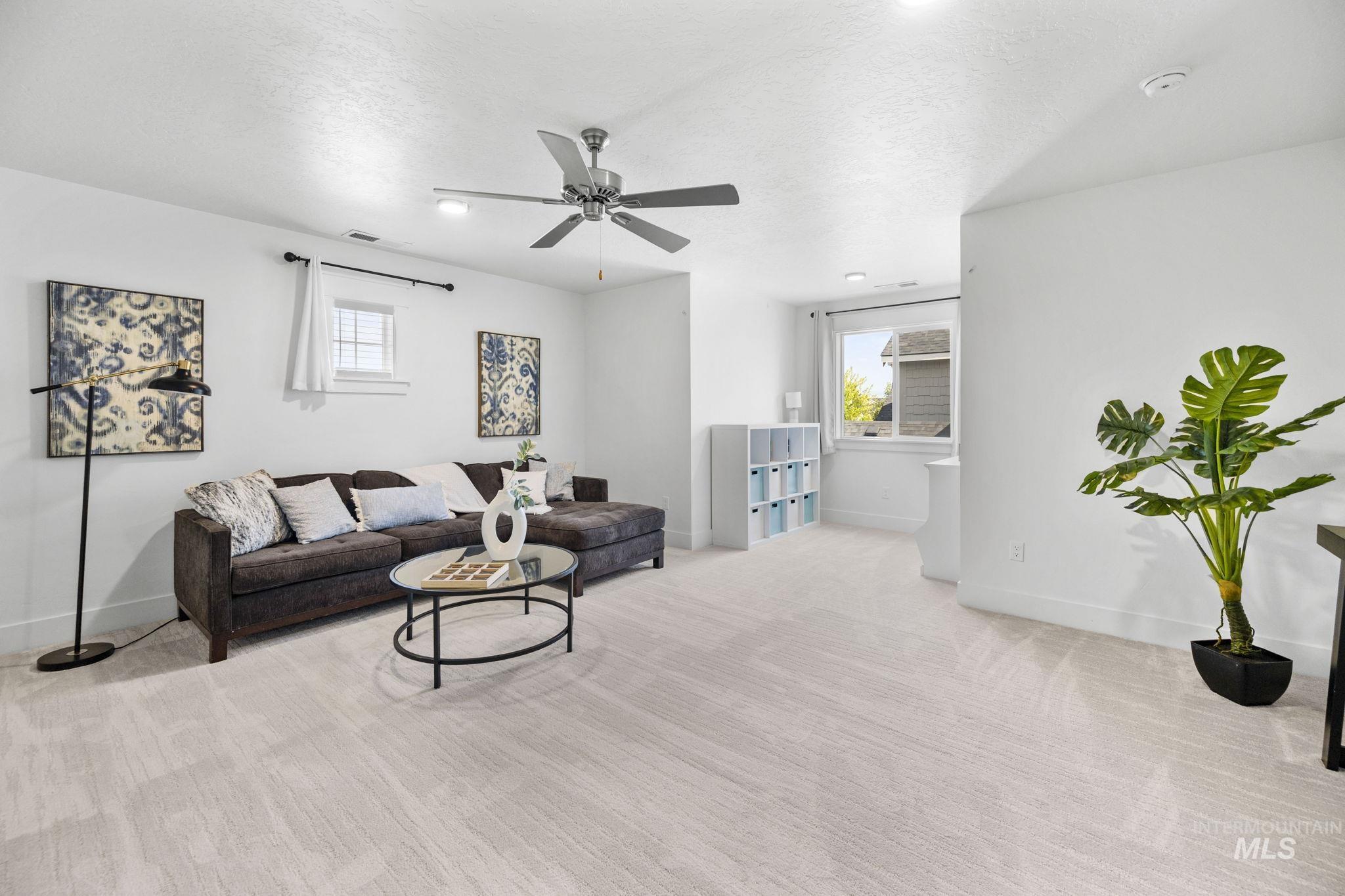 Upstairs Bonus Room w carpeted living area with a textured ceiling, plenty of natural light, and a ceiling fan