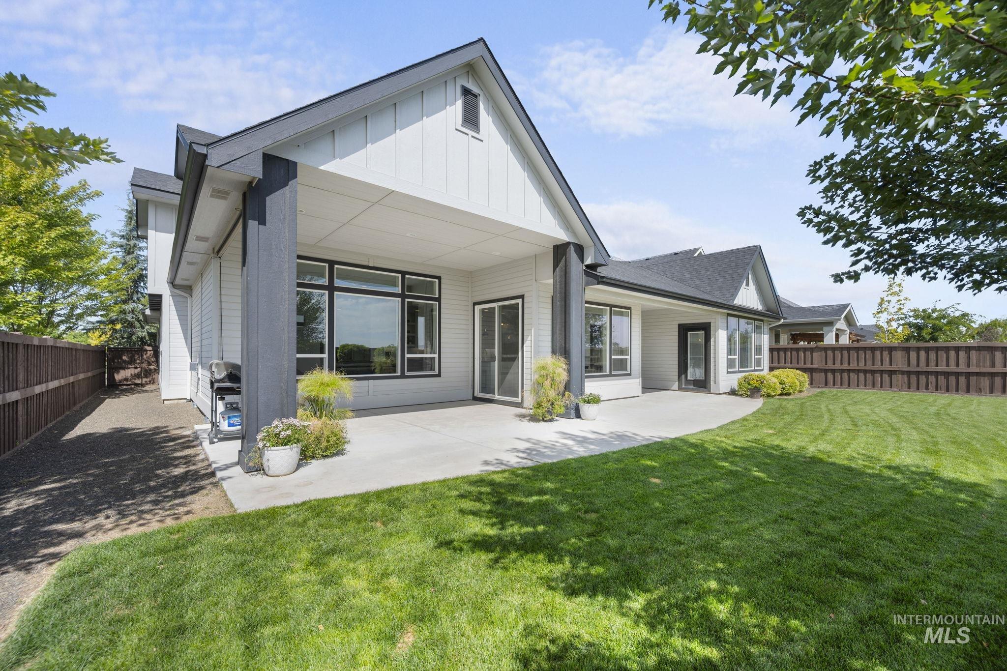 Rear view of house featuring a fenced backyard, a covered patio, and board and batten siding