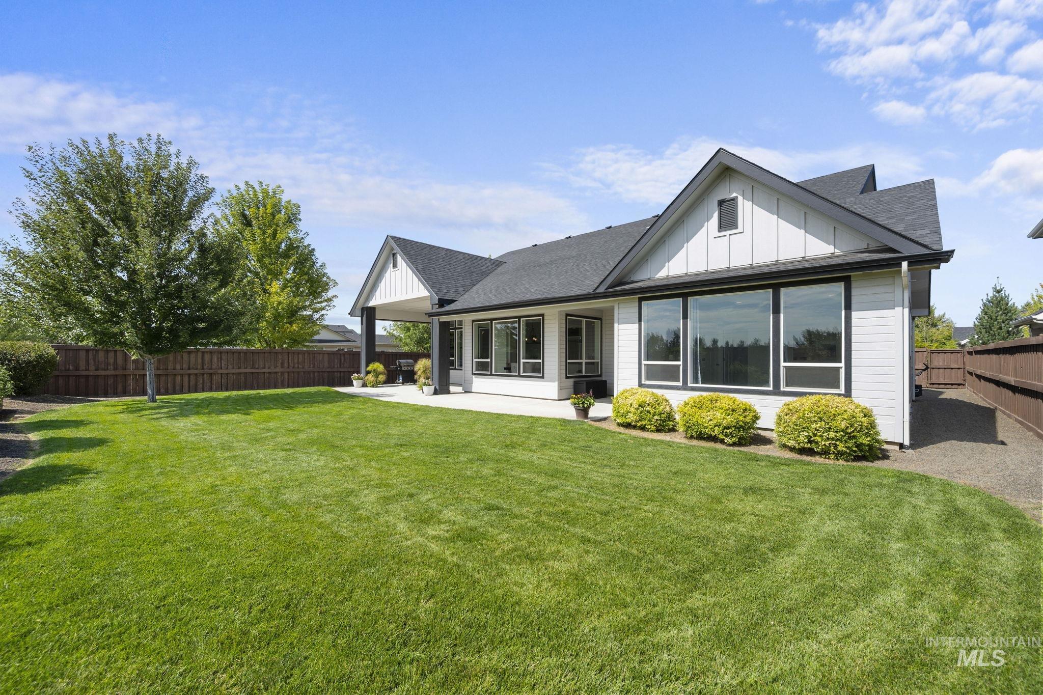 Rear view of house featuring a fenced backyard, roof with shingles, board and batten siding, and a patio