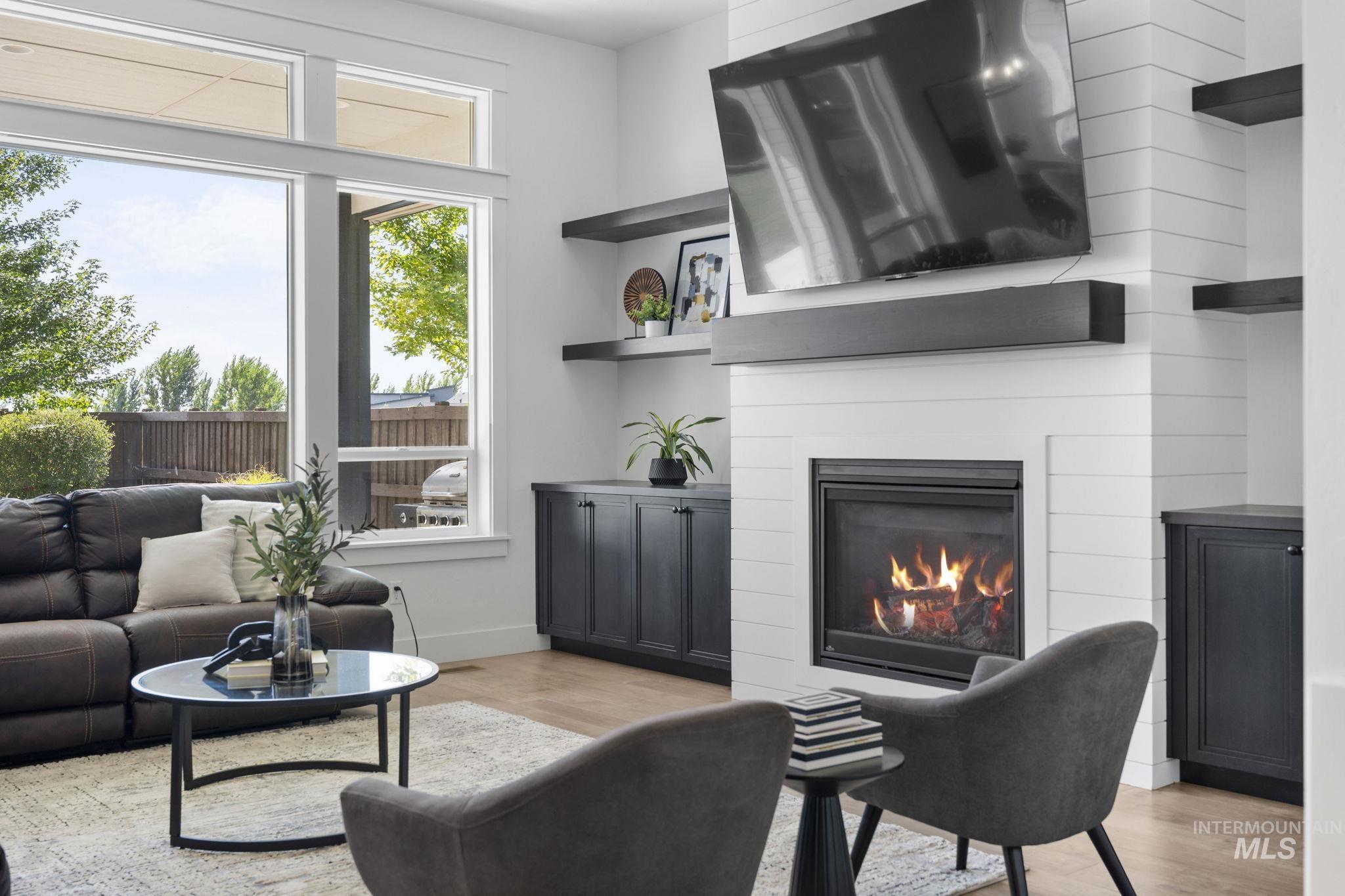 Living area with light wood-style floors and a glass covered fireplace