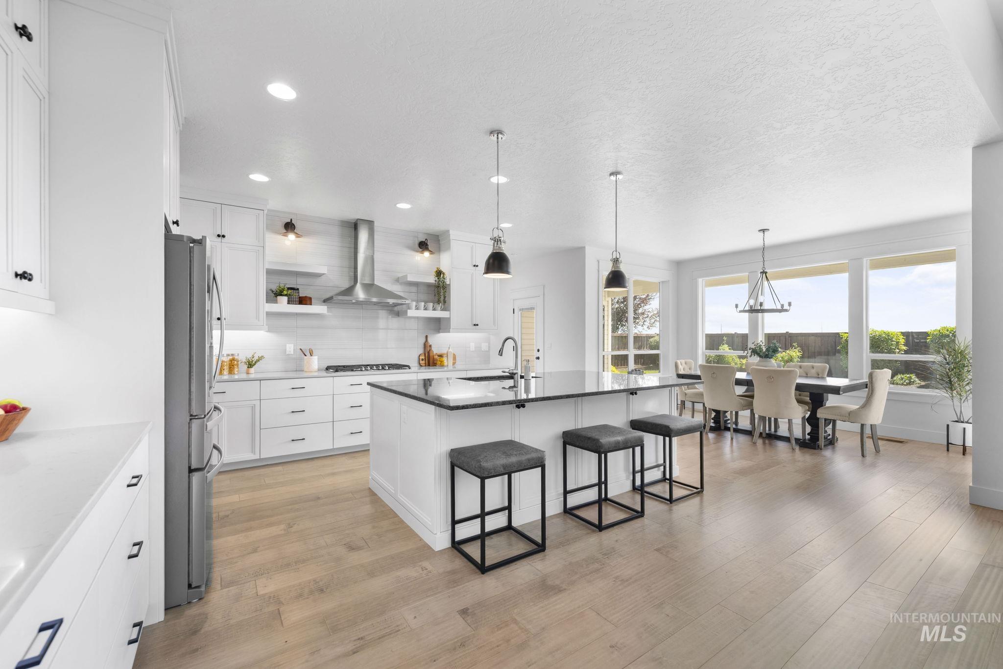Kitchen featuring white cabinetry, decorative light fixtures, a center island with sink, light wood-style flooring, and recessed lighting
