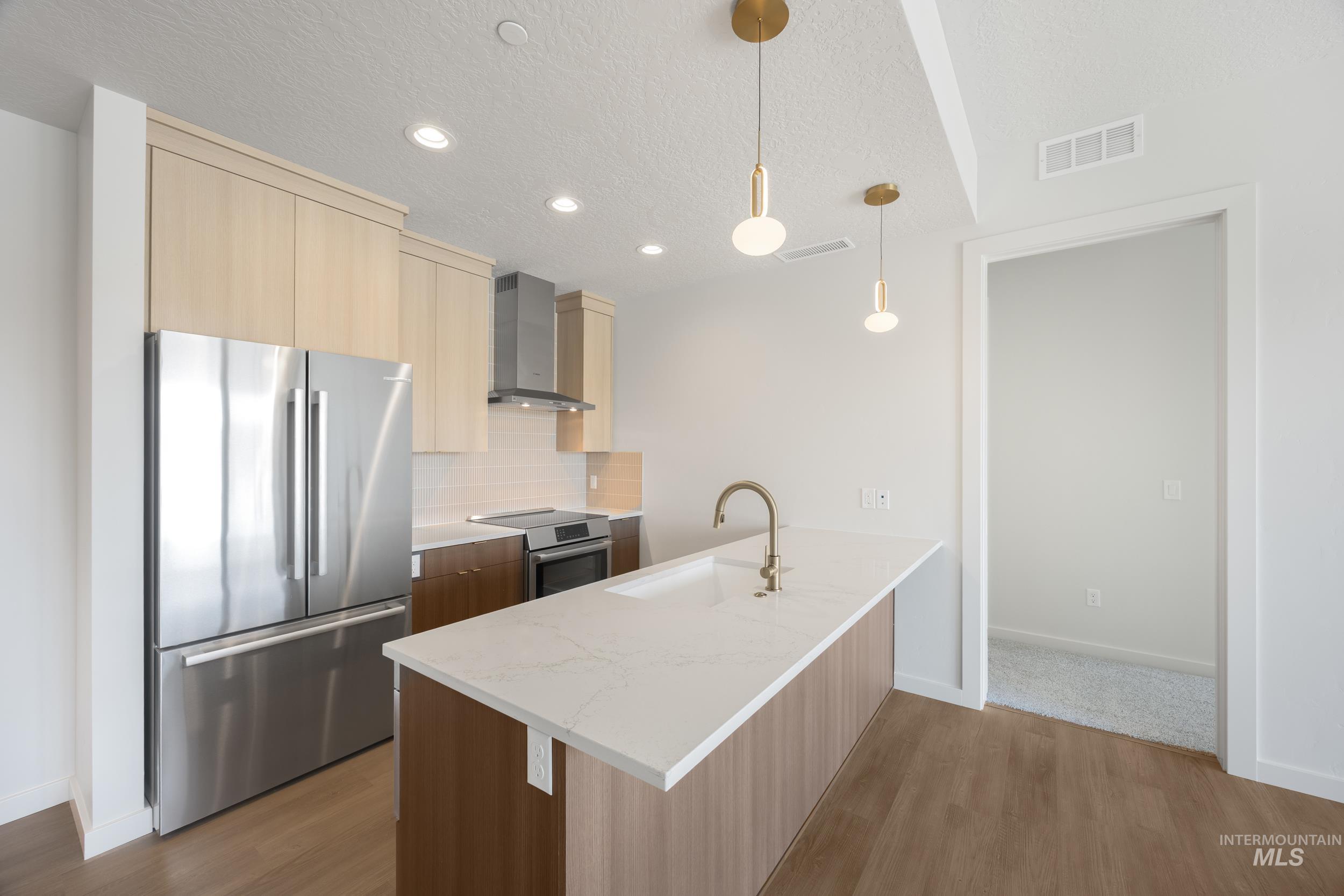 Kitchen featuring modern cabinets, appliances with stainless steel finishes, light stone countertops, a textured ceiling, and dark wood-type flooring