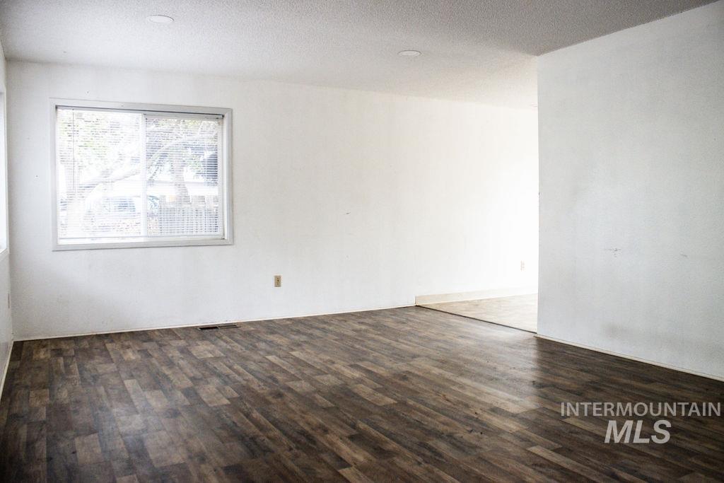Spare room featuring dark wood-style flooring and a textured ceiling