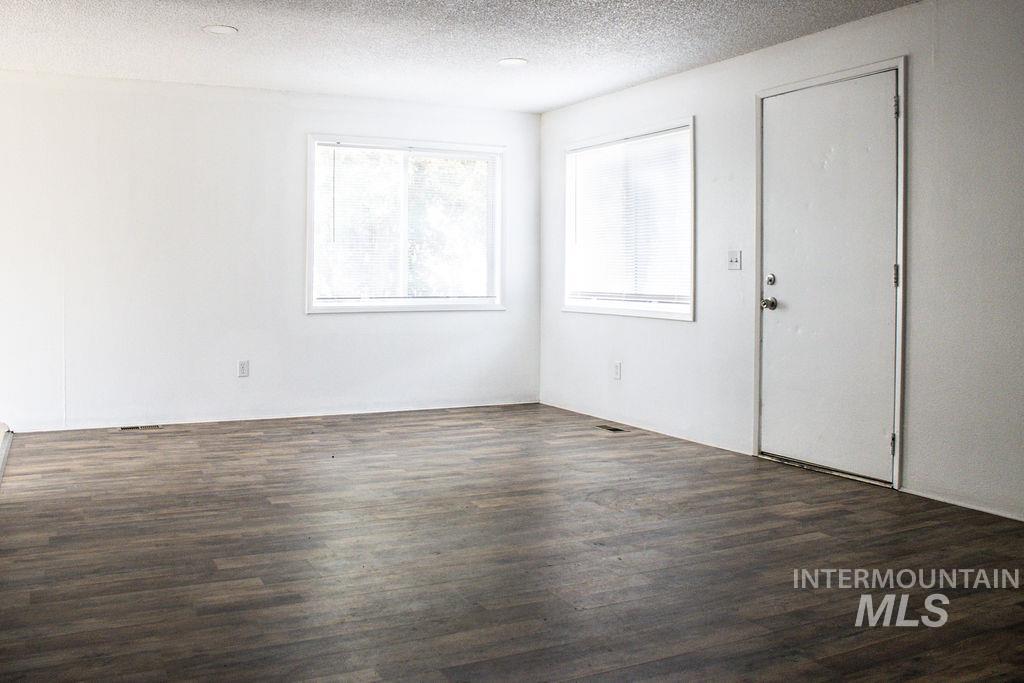 Unfurnished bedroom with a textured ceiling and dark wood-style flooring