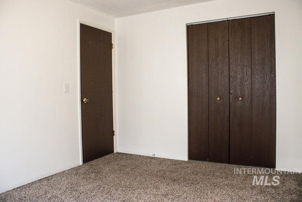 Unfurnished bedroom featuring a closet, carpet flooring, and a textured ceiling