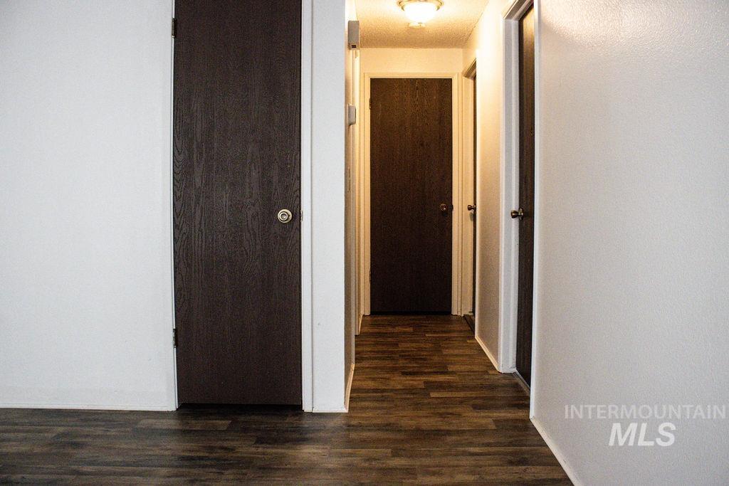 Hallway with dark wood-style flooring and baseboards