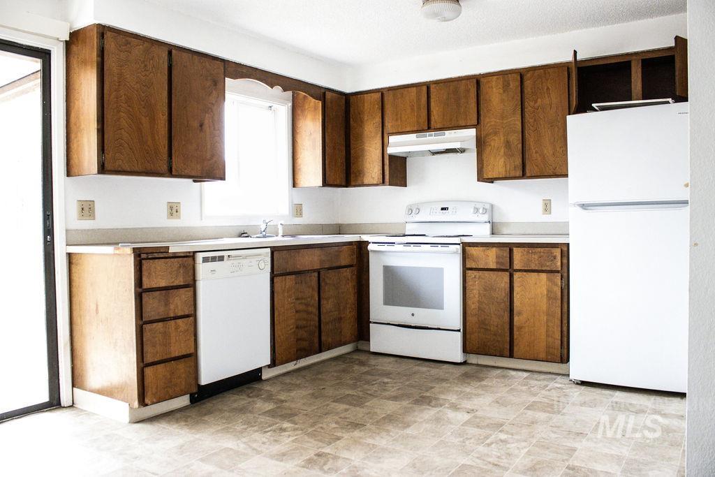 Kitchen with white appliances, light countertops, and under cabinet range hood