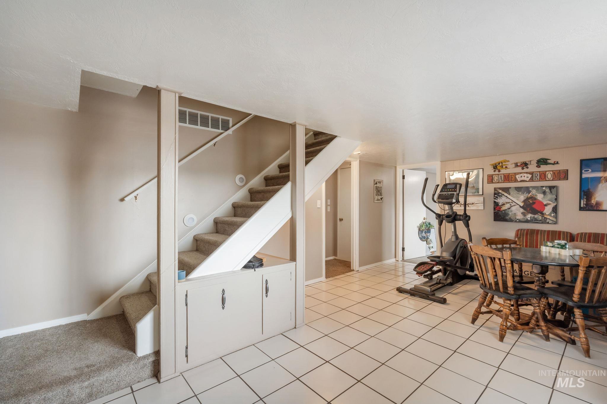 Exercise area featuring light tile patterned flooring and baseboards