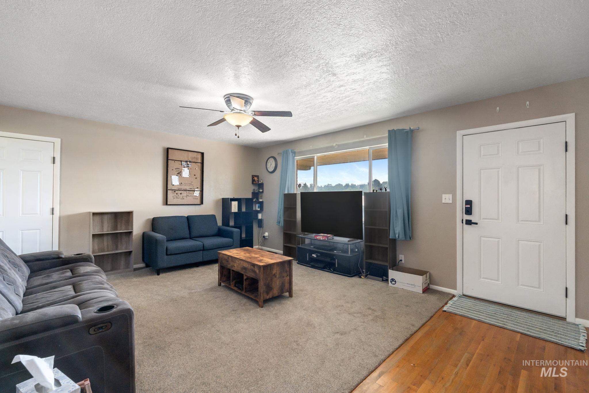 Living area with a textured ceiling, wood finished floors, and a ceiling fan