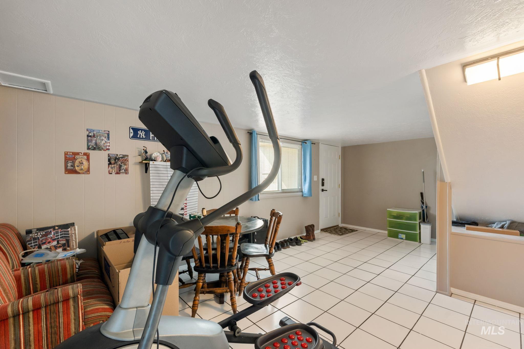Exercise room with light tile patterned flooring and a textured ceiling