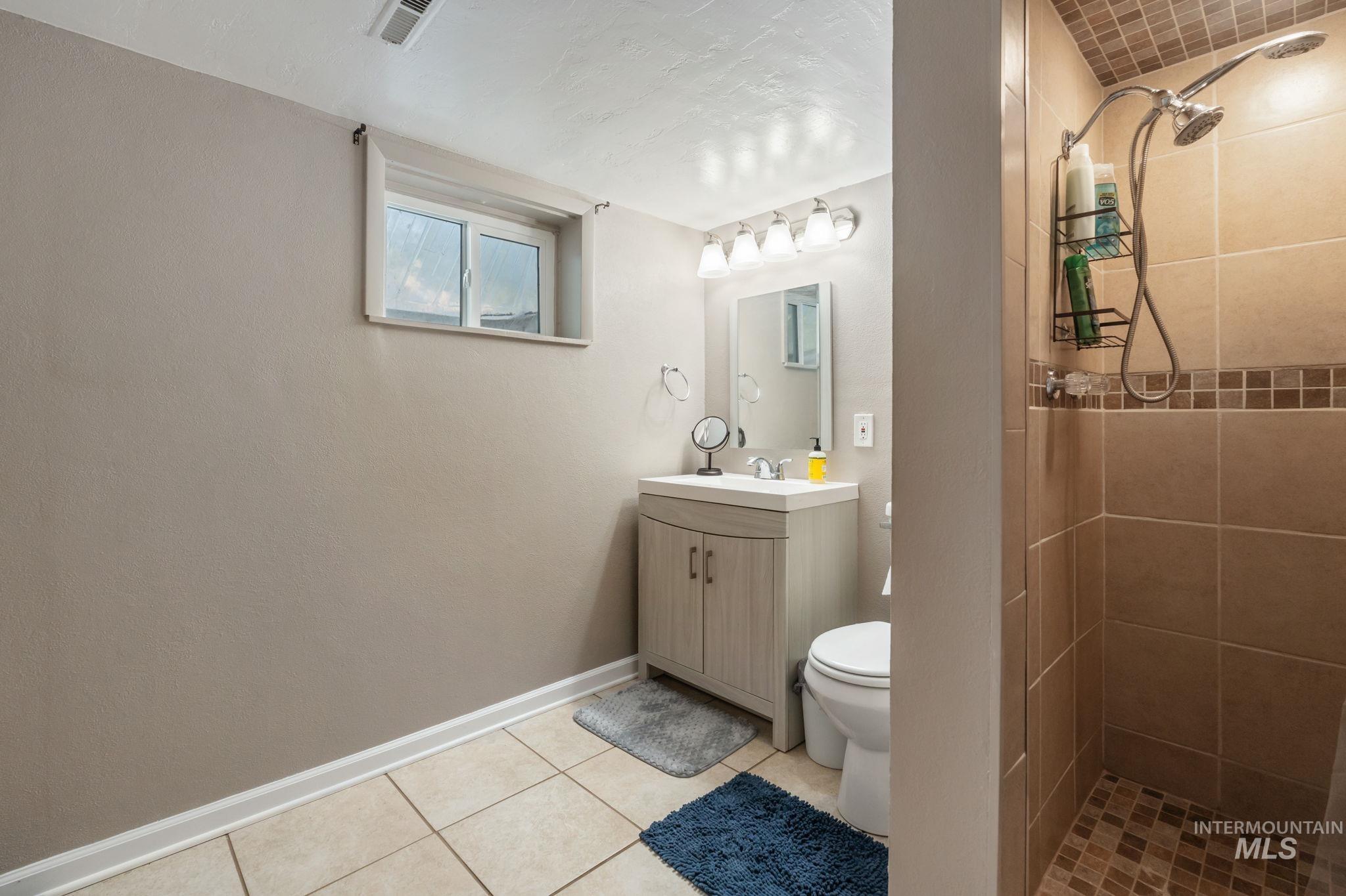 Full bathroom with a shower stall, vanity, and light tile patterned flooring