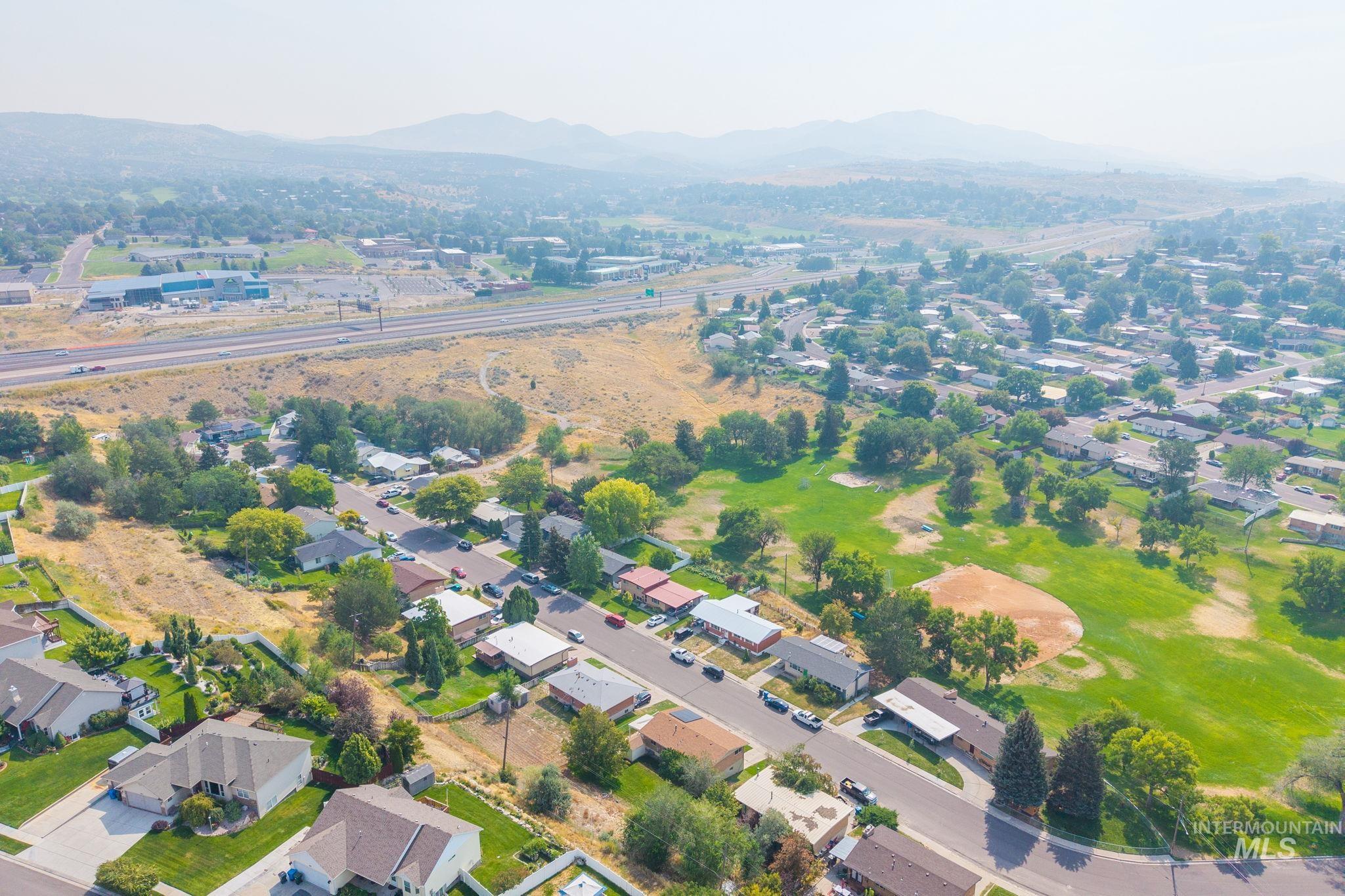 Aerial view of property and surrounding area featuring a mountainous background and nearby suburban area