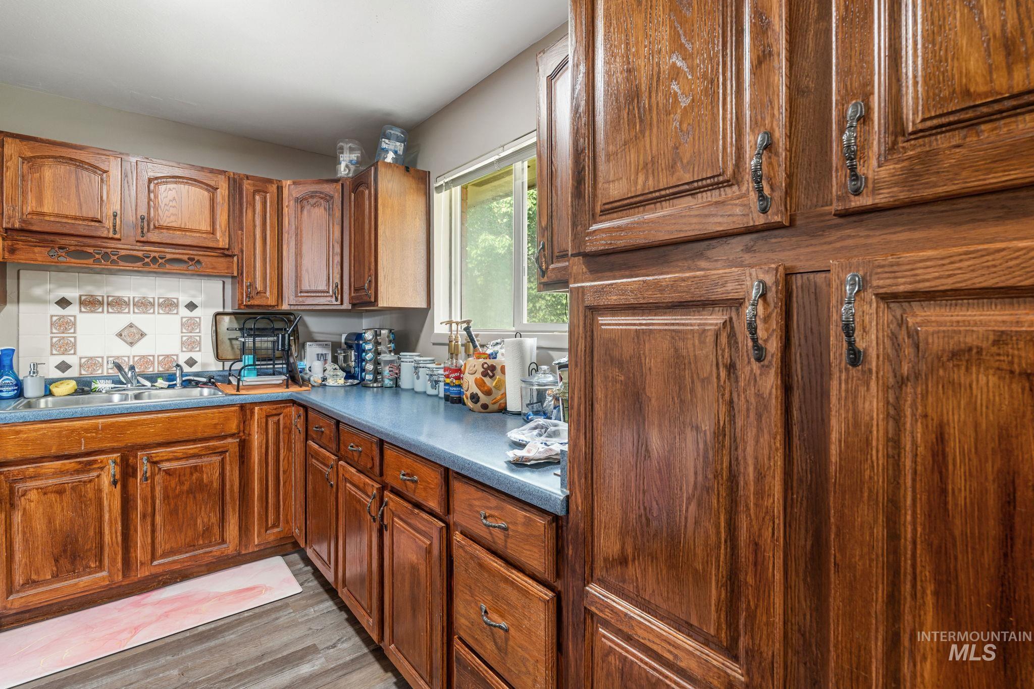 Kitchen with brown cabinetry, dark countertops, and light wood-type flooring