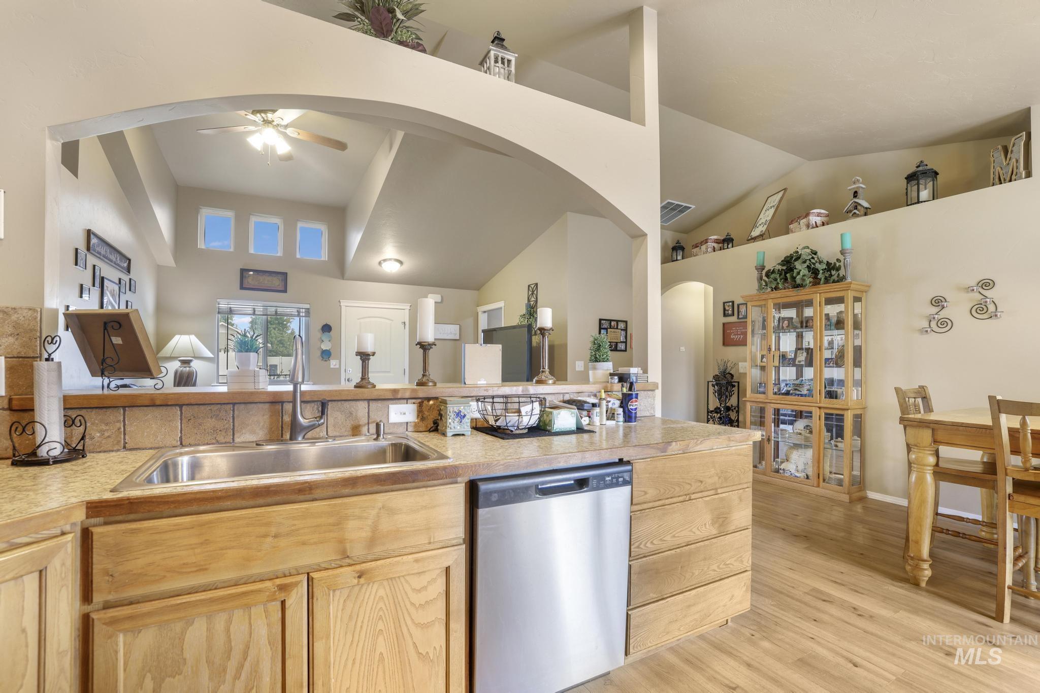 Kitchen with dishwasher, light countertops, light wood-style floors, light brown cabinets, and arched walkways