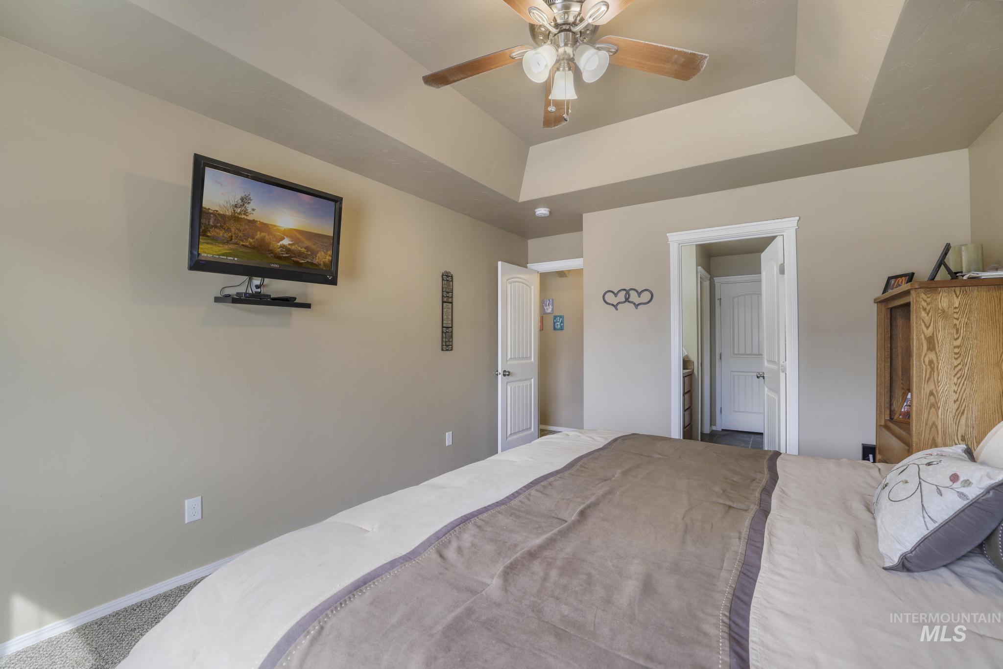 Bedroom with a tray ceiling, carpet, and ceiling fan