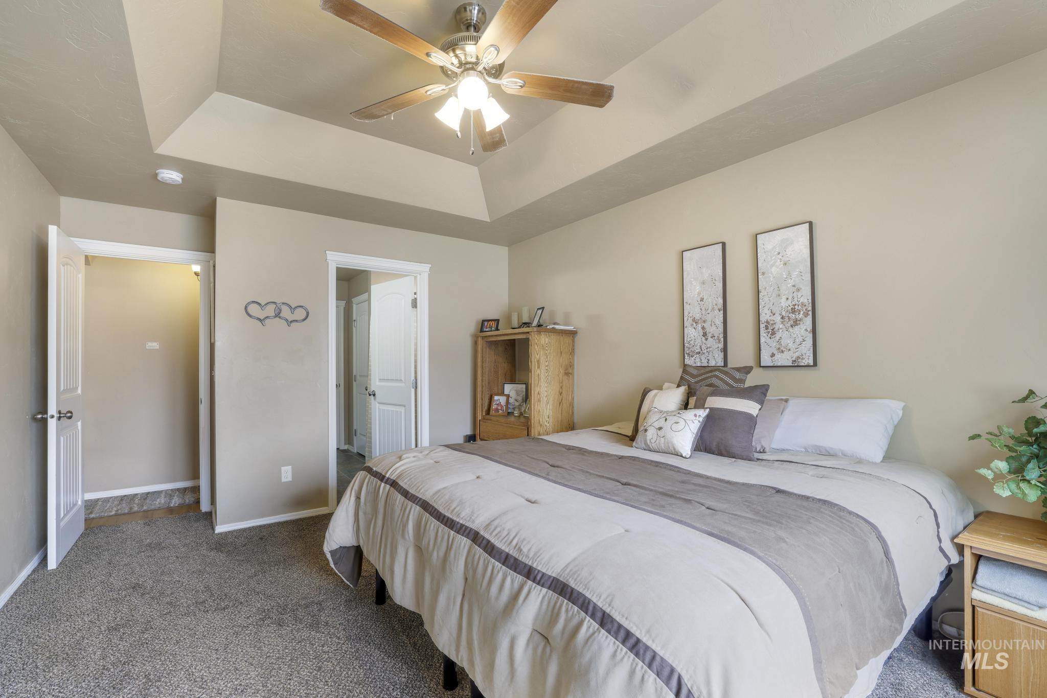Bedroom featuring a raised ceiling, carpet, and ceiling fan