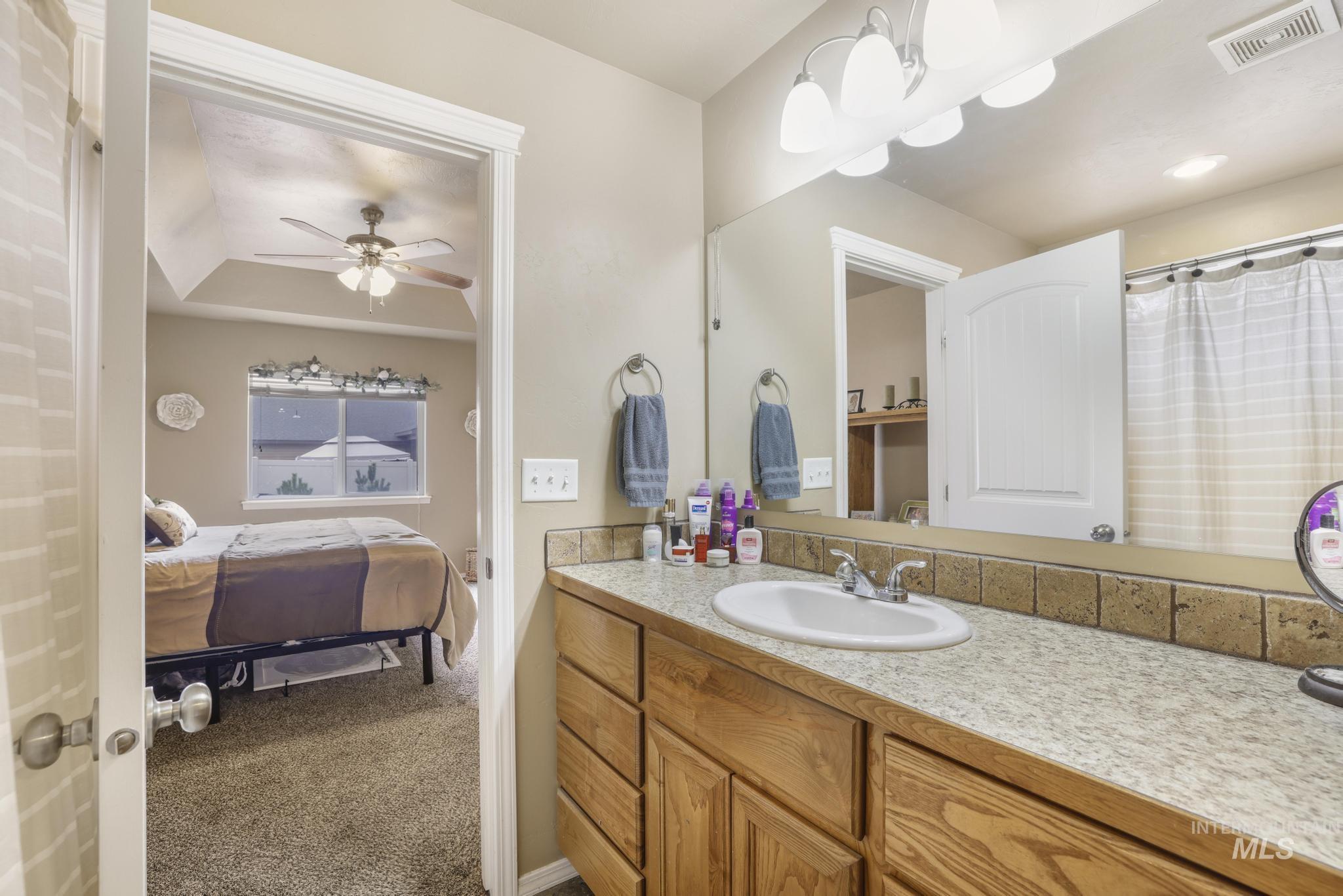 Full bathroom with vanity, ensuite bath, ceiling fan, and curtained shower