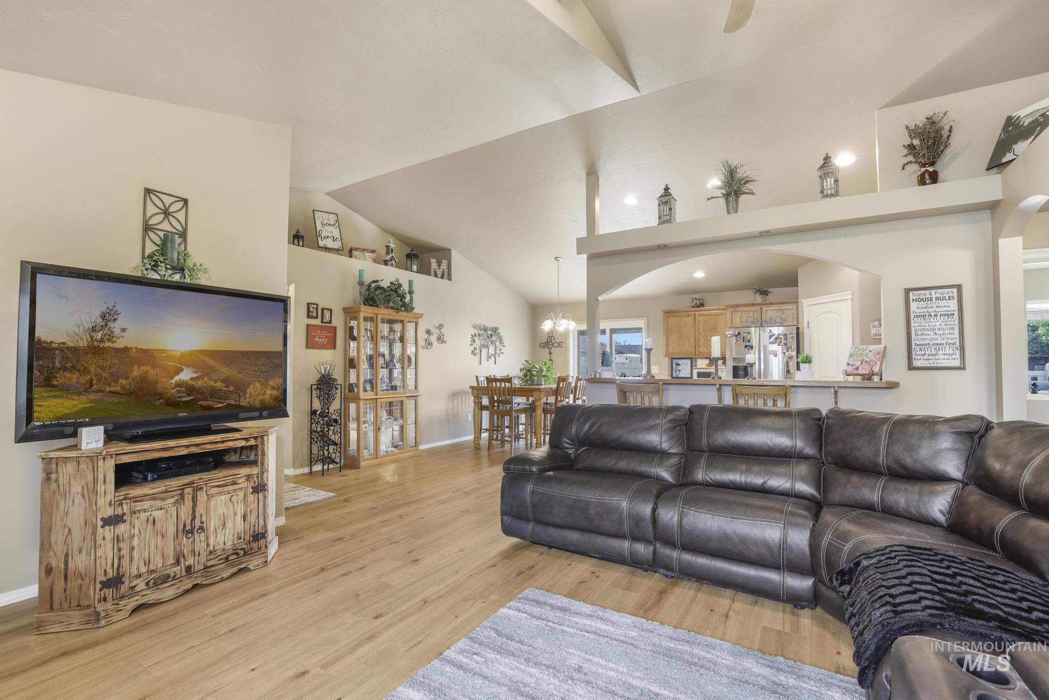 Living area with light wood-style floors, a chandelier, and high vaulted ceiling