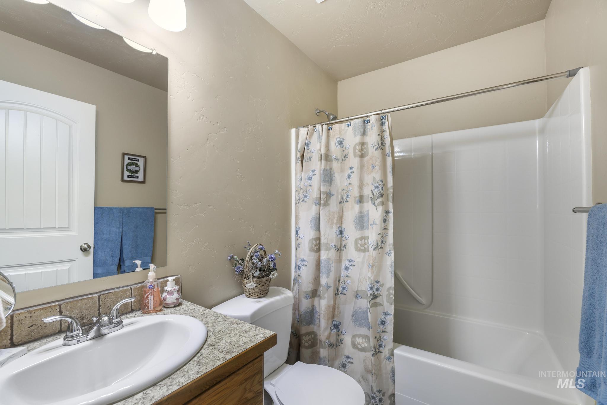Full bath with shower / bath combo, vanity, and a textured wall