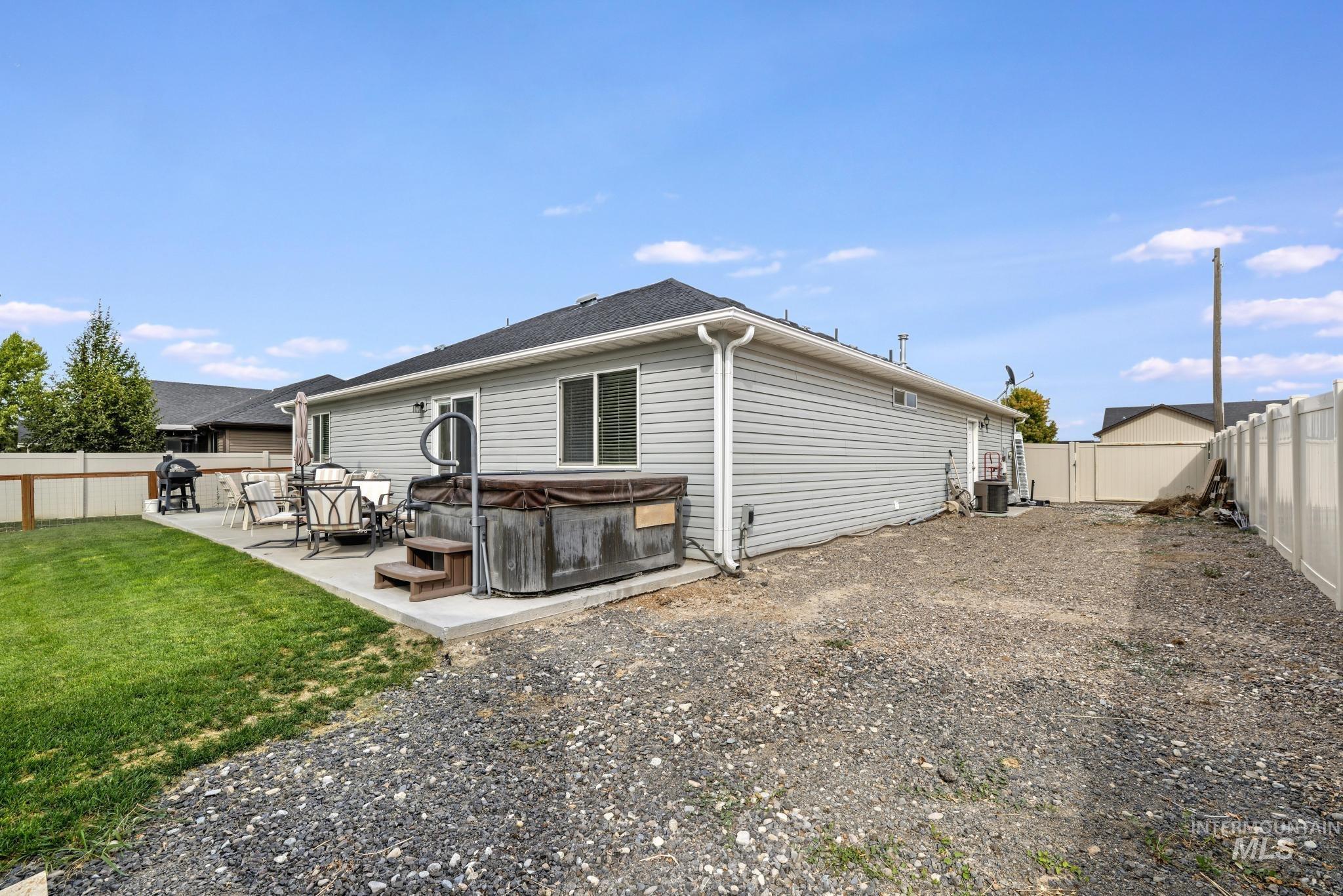 Back of house featuring a fenced backyard, a hot tub, and a patio