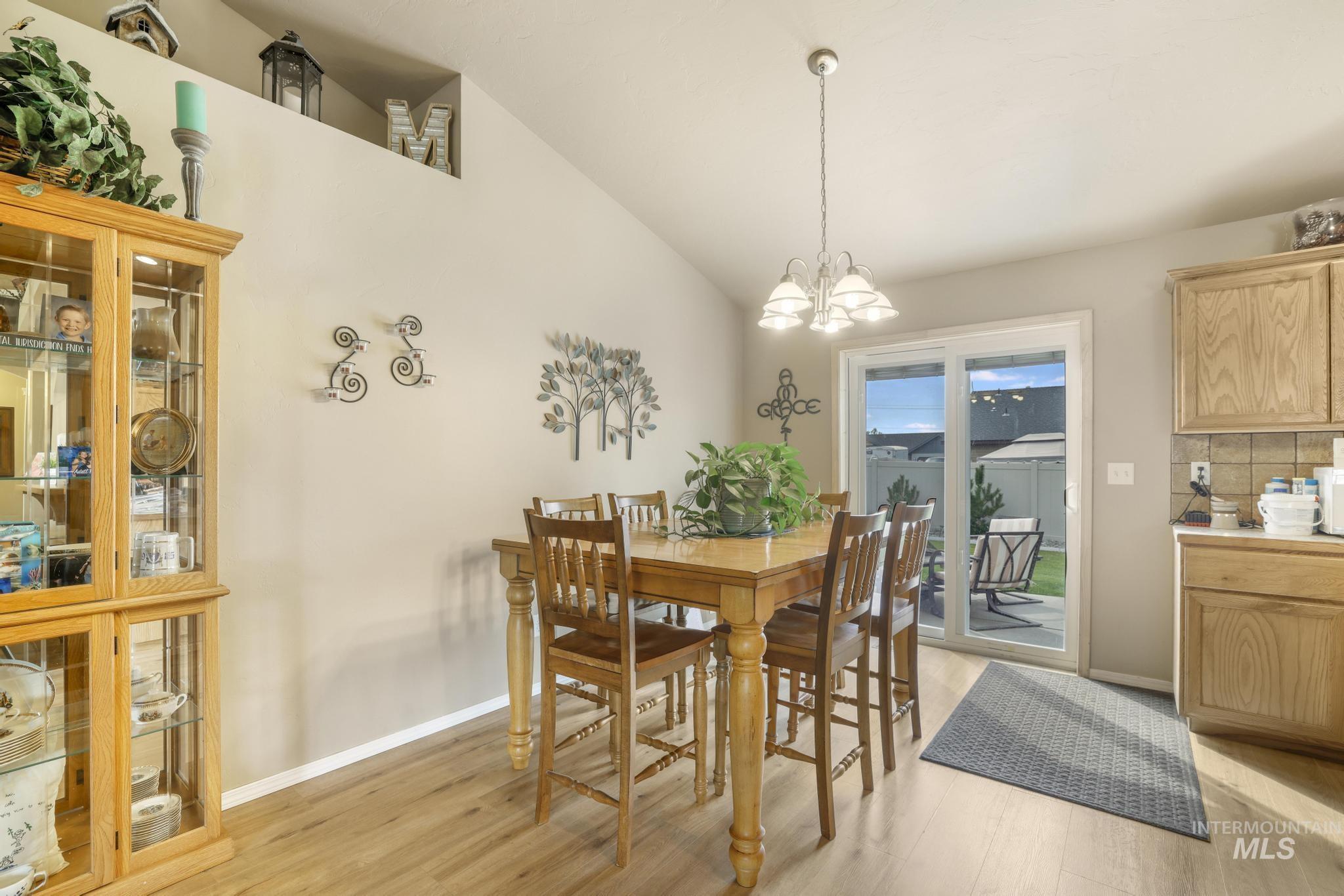 Dining space featuring light wood-style flooring, lofted ceiling, and a chandelier