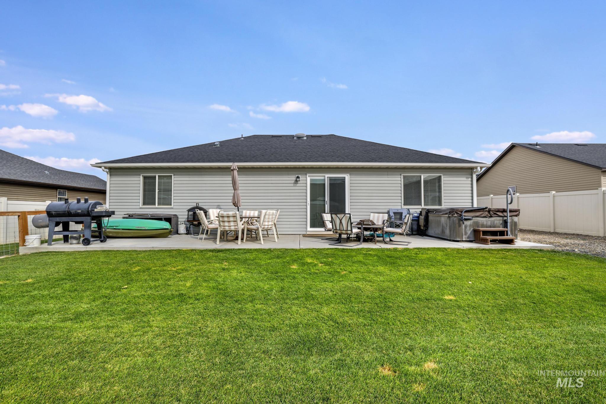 Back of property featuring a hot tub, a patio area, a fenced backyard, and a shingled roof