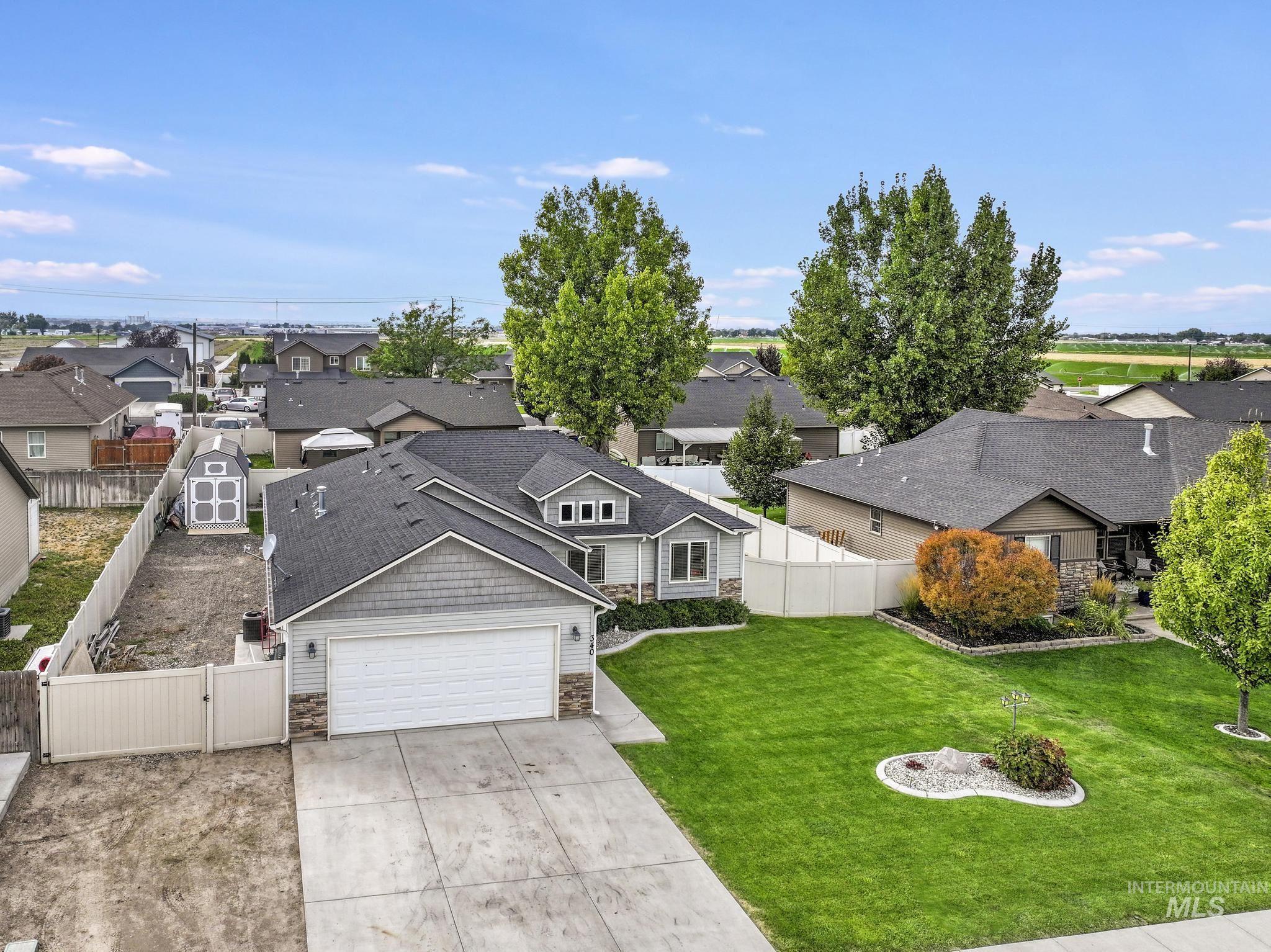 View of front of property with a residential view, stone siding, a gate, concrete driveway, and a garage